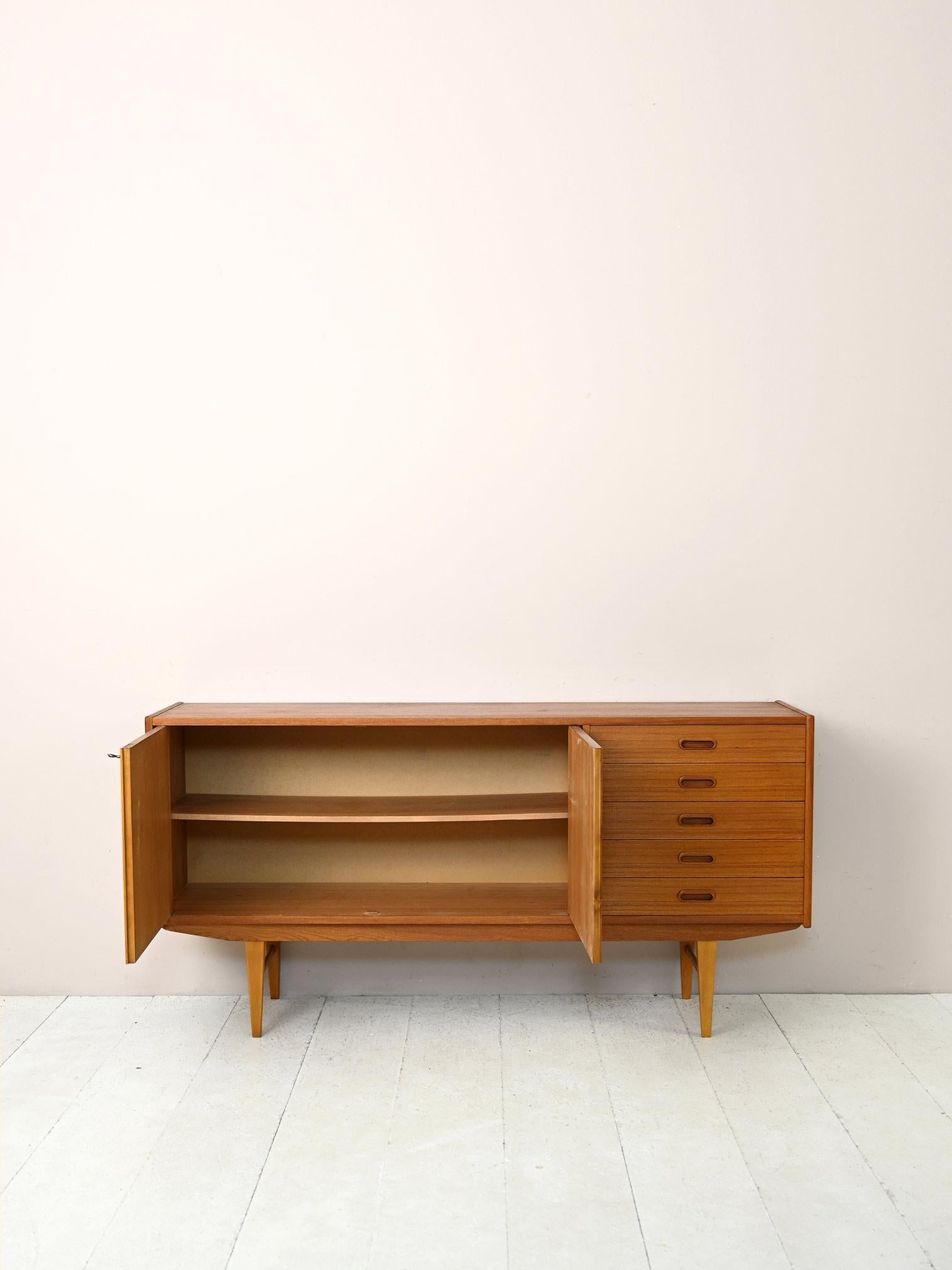 Original vintage Scandinavian sideboard from the 1960s.

A modern piece of furniture with retro charm that, thanks to its minimalist style, fits well in contemporary environments. The teak frame features 5 drawers on one side and a storage
