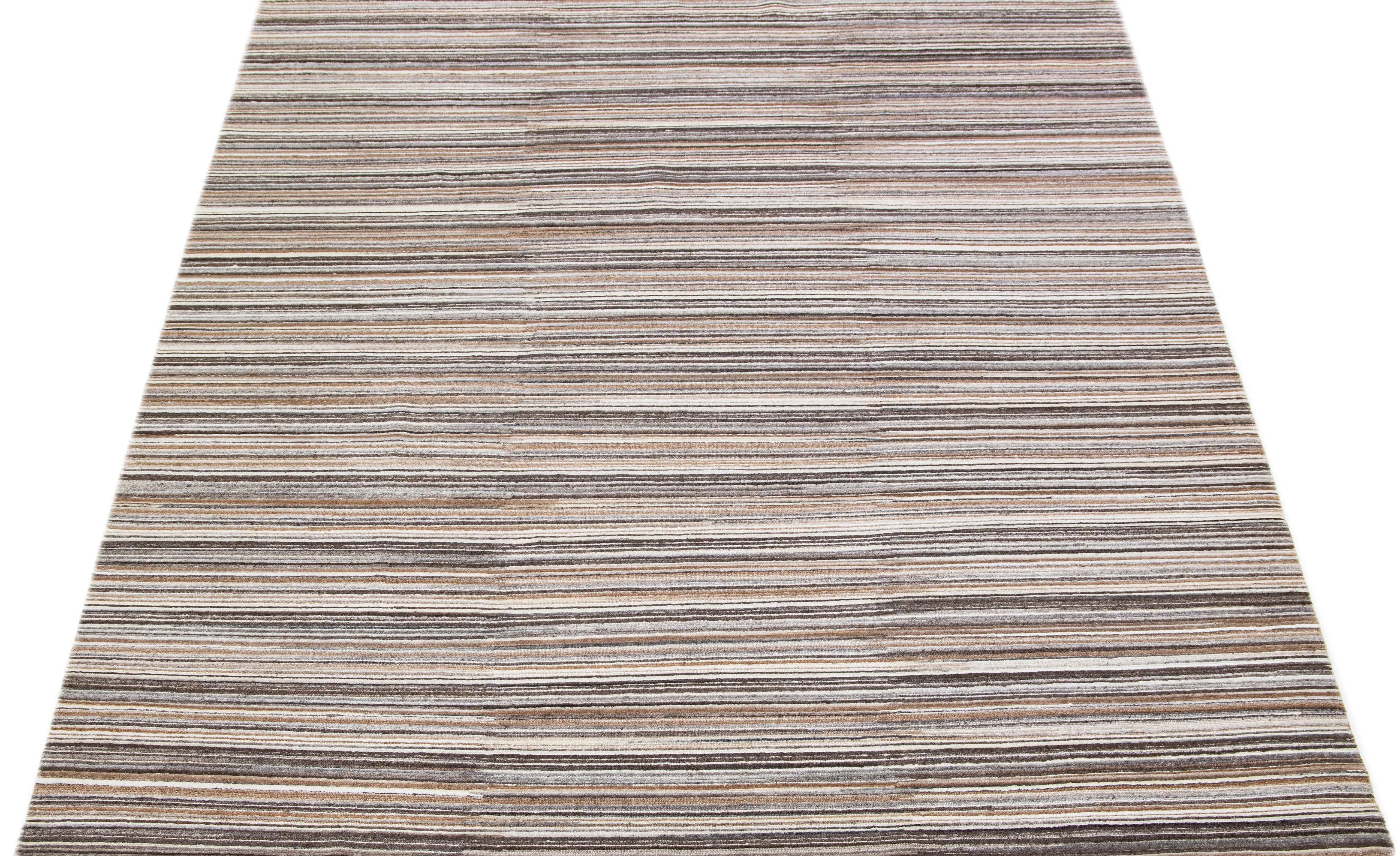 Bellissimo tappeto indiano in bambù e seta fatto a mano da Apadana con campo di colori beige, grigio e marrone. Questo tappeto della collezione Groove ha un design a righe all-over.

Questo tappeto misura 8' x 10'.

Colori e dimensioni