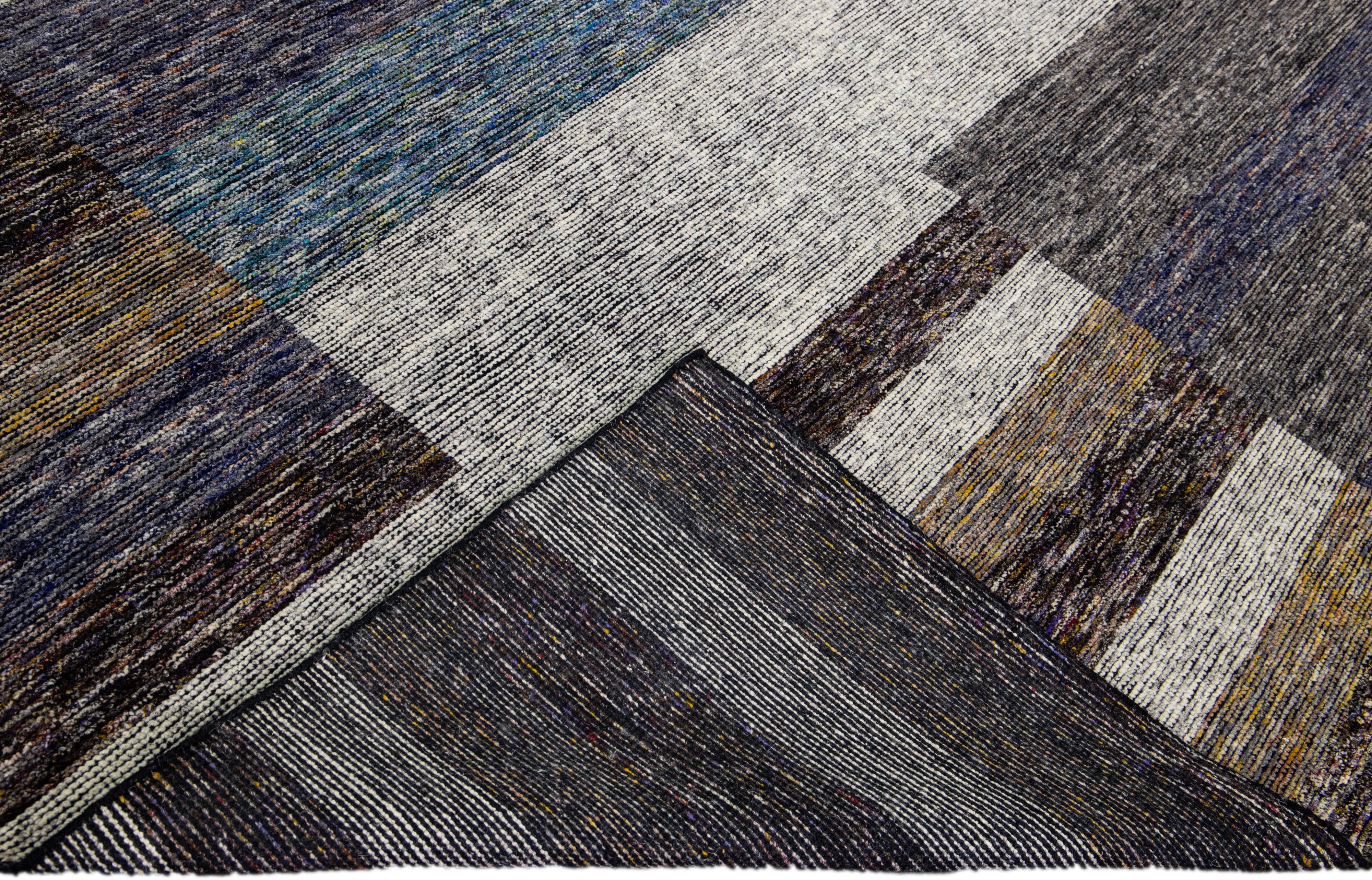 Beautiful modern Apadana's Safi Collection hand-knotted wool rug with an earthy colors field. This Modern rug has blue, gray, and brown accents a gorgeous layout Abstract design.

This rug measures: 10' x 14'2''.

Our rugs are professional