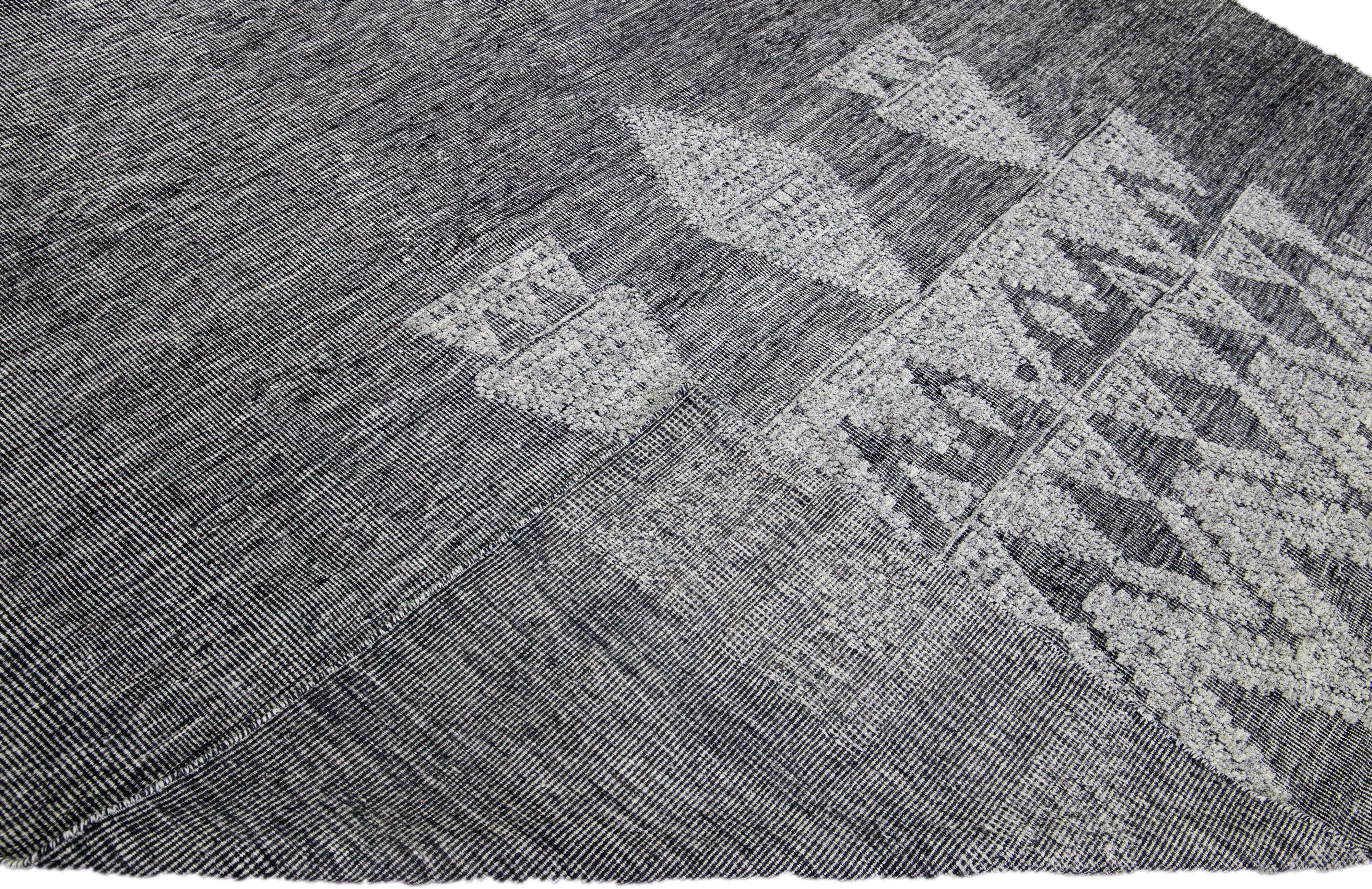 Schöner moderner Teppich aus der Safi Collection'S von Apadana aus handgeknüpfter Wolle mit dunkelgrauem Farbfeld. Dieser moderne Teppich hat graue Akzente in einem herrlichen geometrischen Muster.

Dieser Teppich misst: 10'1