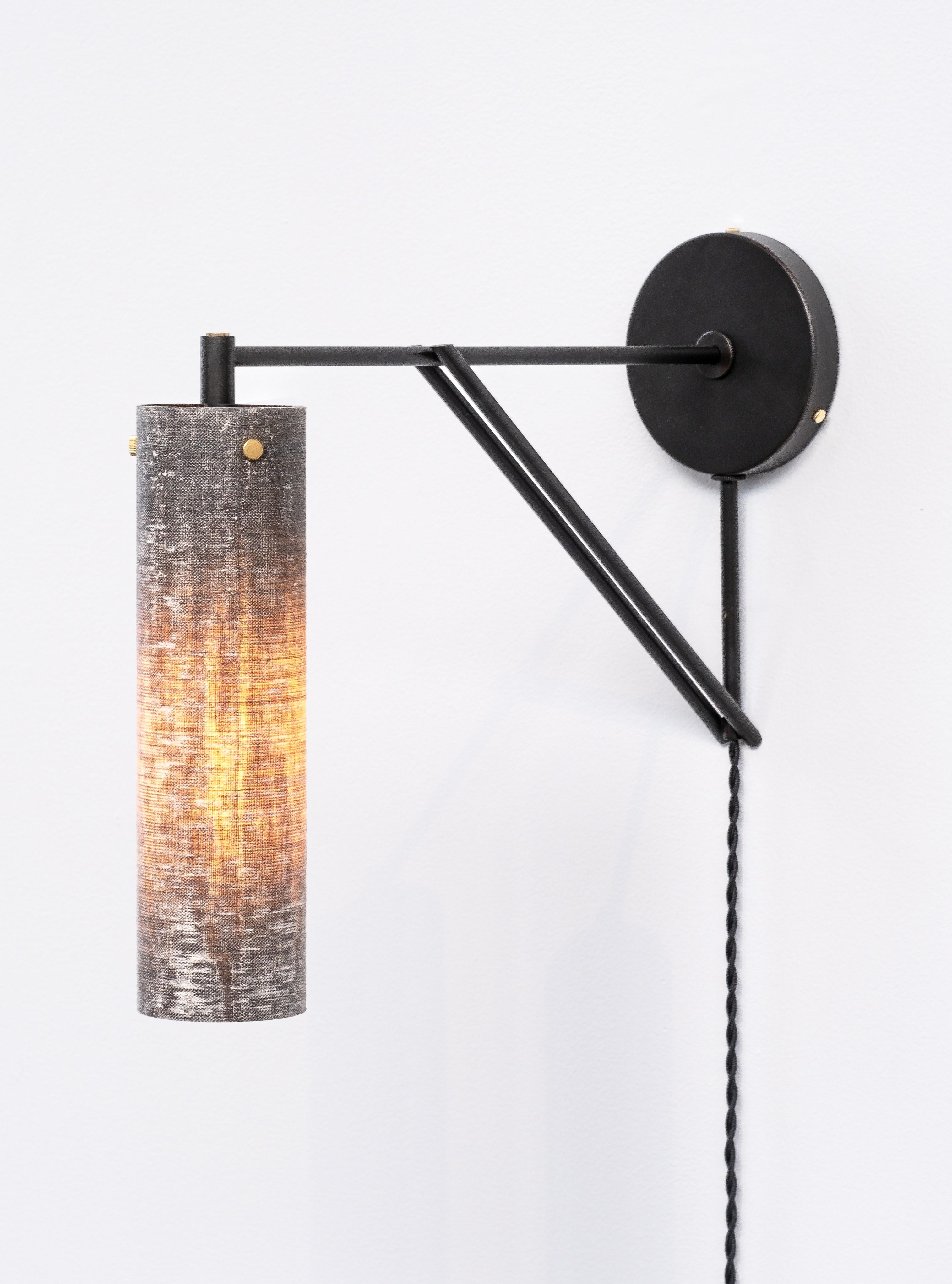 La Tikal Armed Sconce è riconoscibile per il nostro caratteristico paralume in micarta, realizzato a mano in lino e resina. 
Il paralume leggero produce una luce soffusa e un interesse visivo sia da acceso che da spento.  Il paralume cilindrico