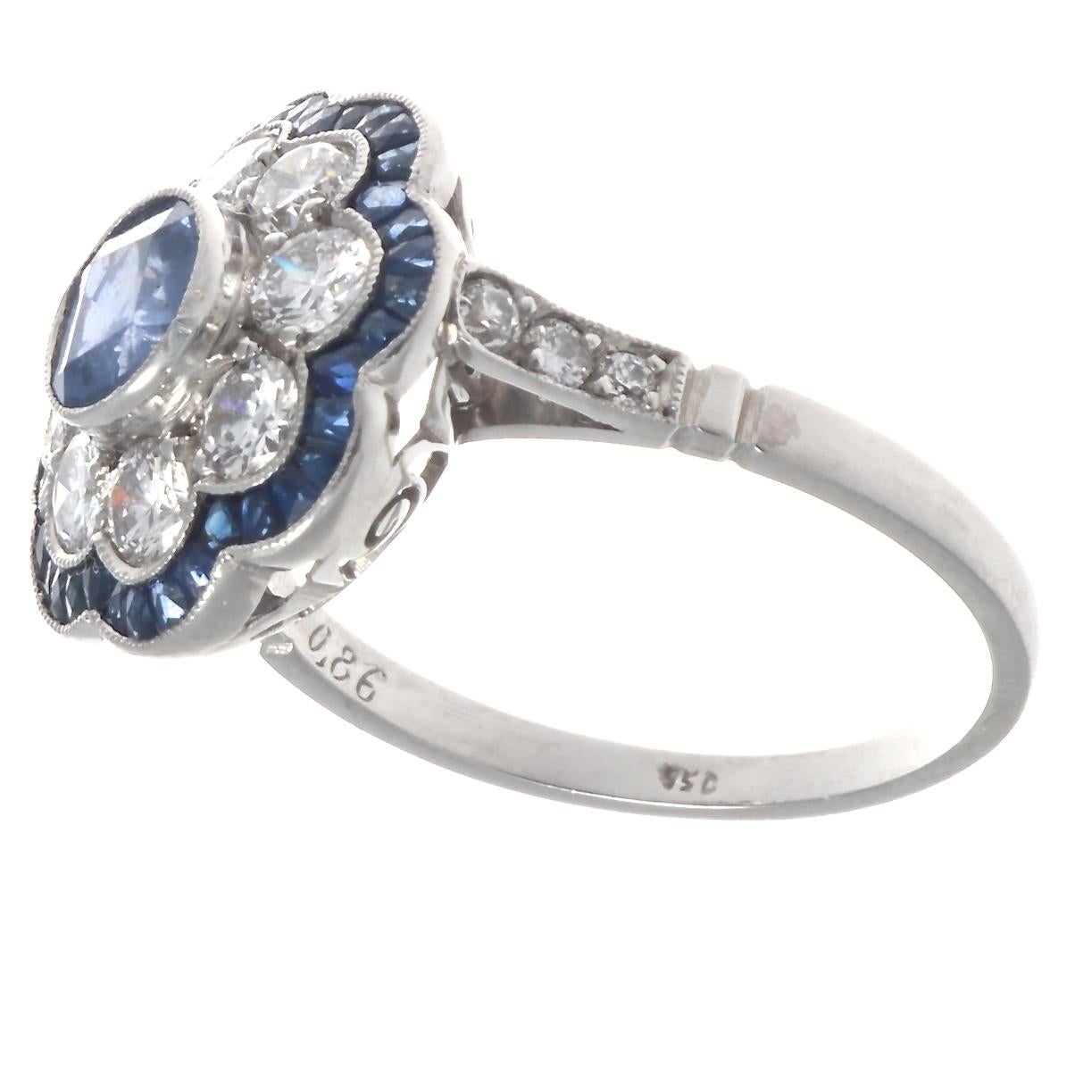 A sapphire and diamond cluster ring that features a beautiful faceted round 0.86 ct. sapphire surrounded by 8 round brilliant diamonds that make up a sparkling flower. The diamonds weigh approximately 0.80 cts. are are graded H-I color, VS clarity.