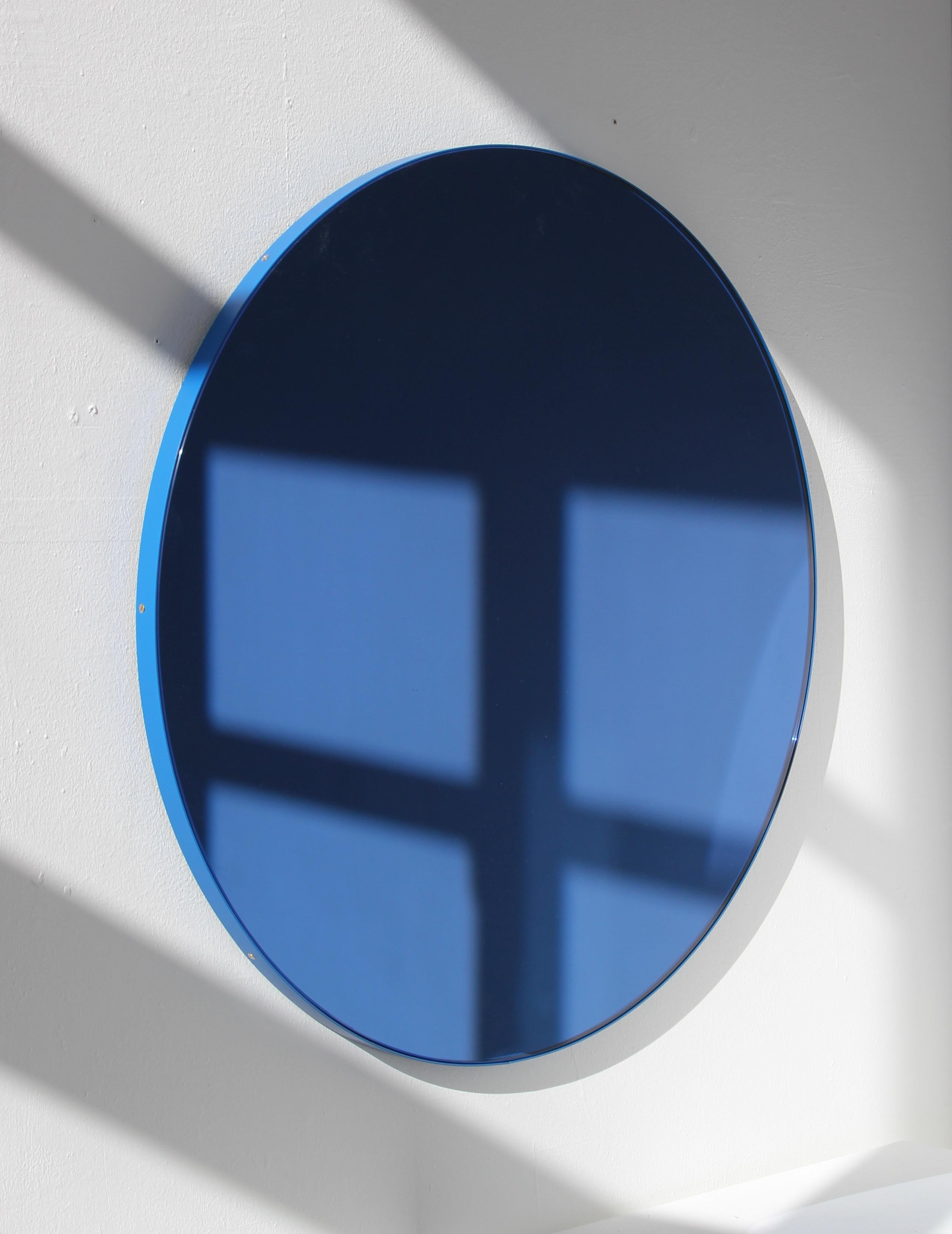 Miroir rond contemporain teinté bleu avec un cadre en aluminium peint par poudrage bleu. Conçue et fabriquée à la main à Londres, au Royaume-Uni.

Nos miroirs sont conçus avec un système intégré de tasseaux français (lattes fendues) qui garantit que