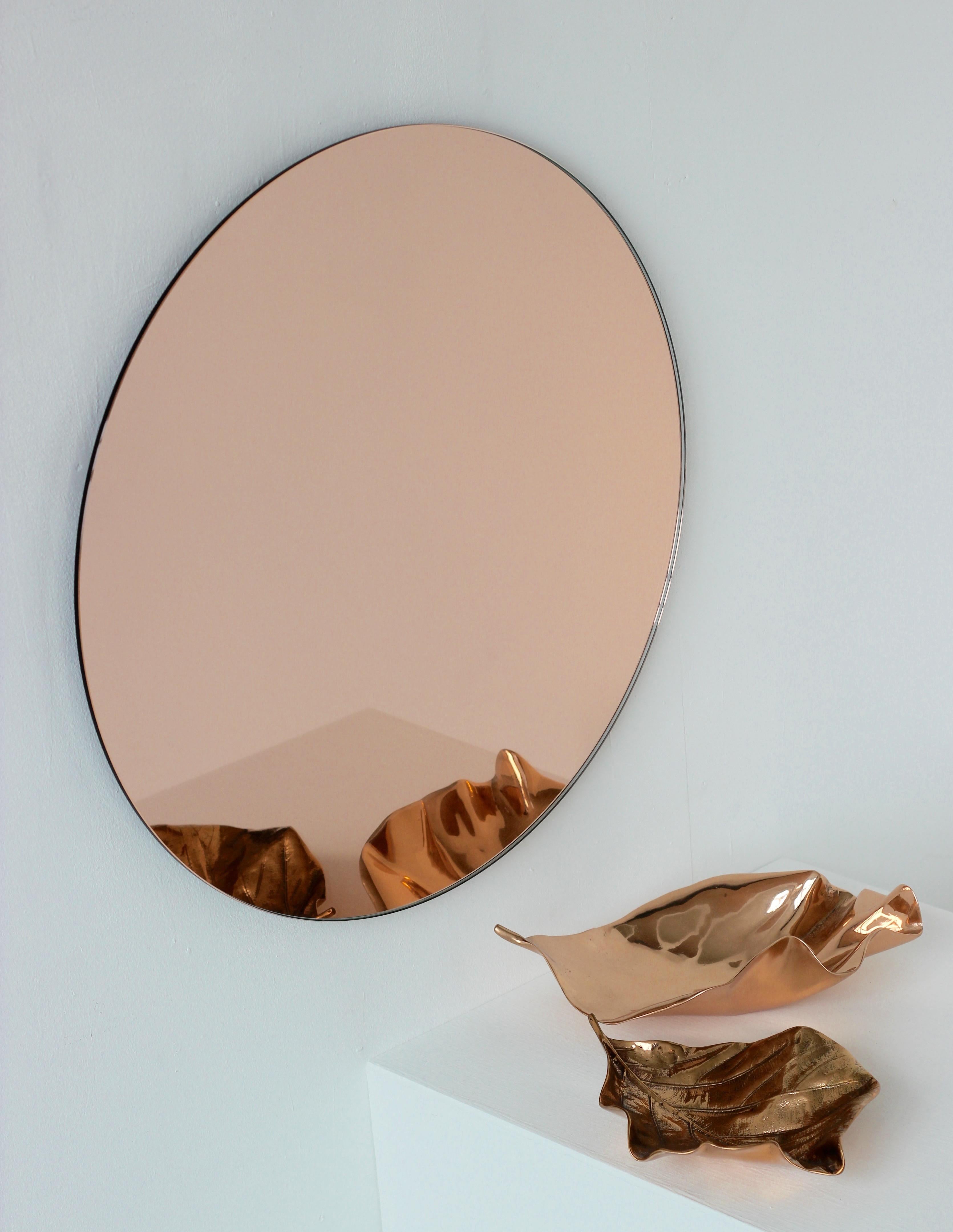 Charming and minimalist rose gold / peach tinted round frameless mirror with a floating effect. Quality design that ensures the mirror sits perfectly parallel to the wall. Designed and made in London, UK.

Fitted with professional plates not visible