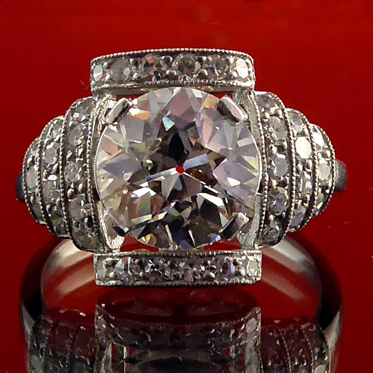 This wonderful old European cut diamond takes centre stage in this show-stopper of a ring that just oozes Art Deco style design elements from the diamond stepped shoulders to the diamond scroll edges.  The diamond measures approx. 8.08mm x 8.10mm x