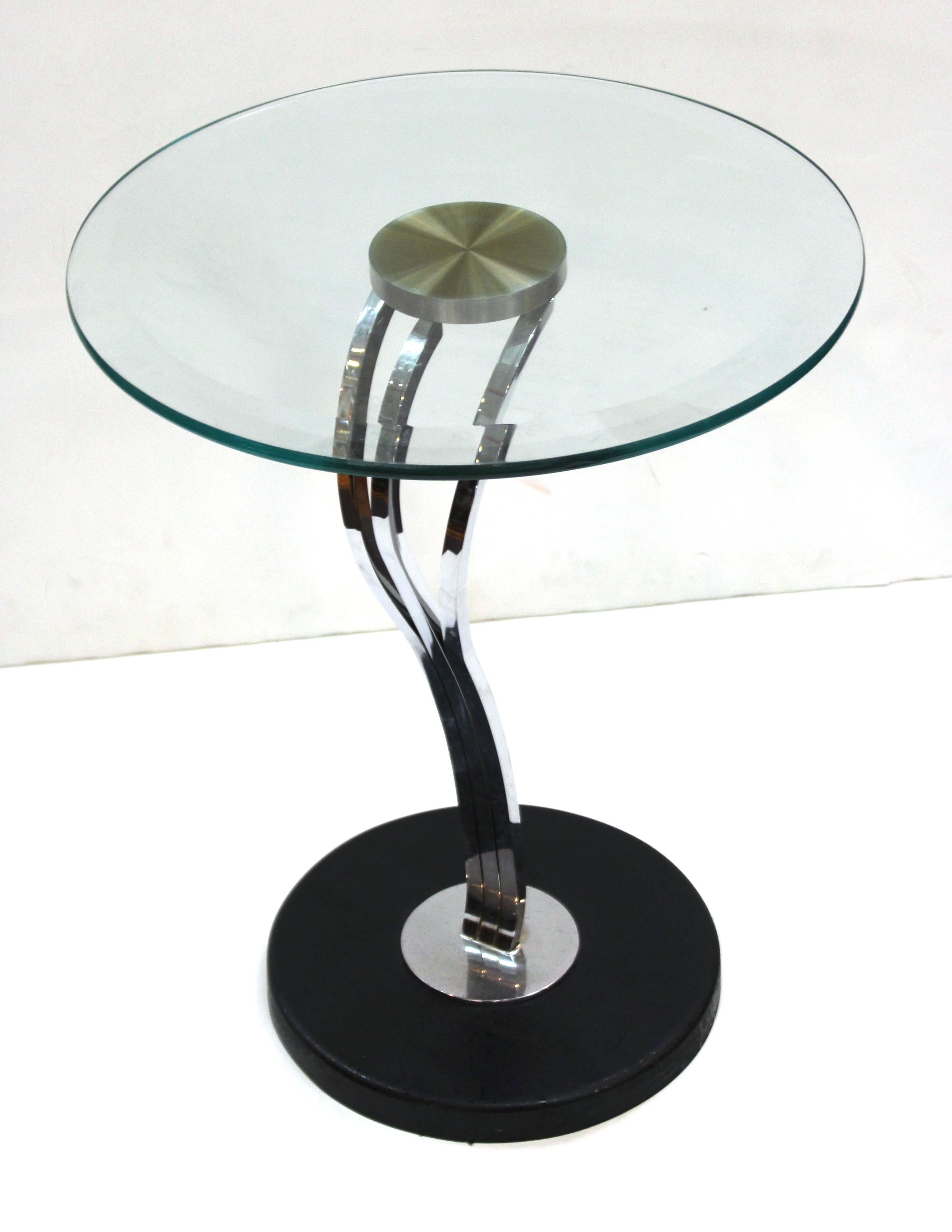 Modern Art Deco style side table or center table. The piece has a swung chromed metal cabriole leg atop a heavy black base and a round glass top. The piece is in great vintage condition with age-appropriate wear and use.