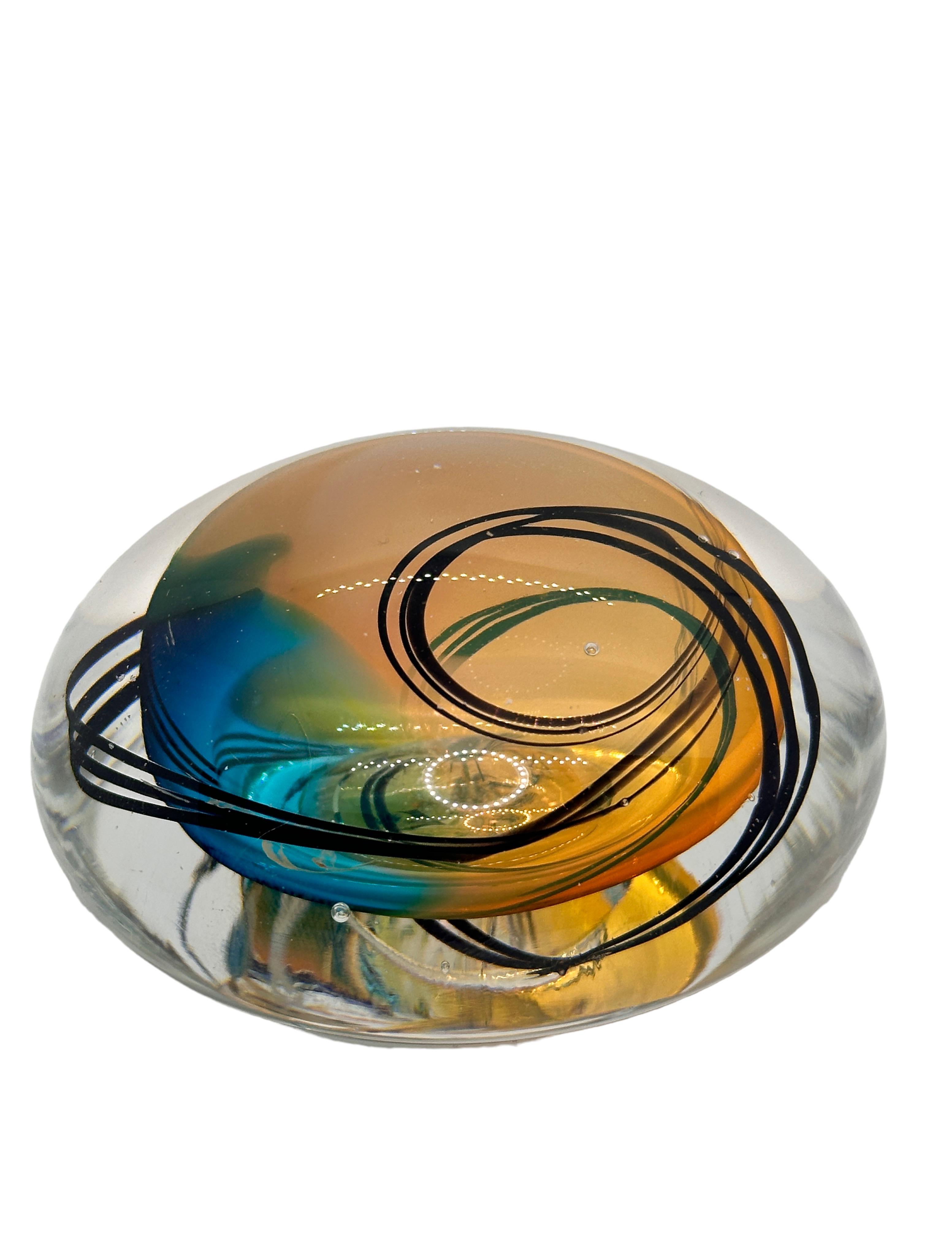 This exquisite paperweight features folded amber, black and blue swirls.
An Artist has been created this glass sculpture. A beautiful way to decorate your office or just to admire. It has unique design, crafted and polished by hand, signed and dated