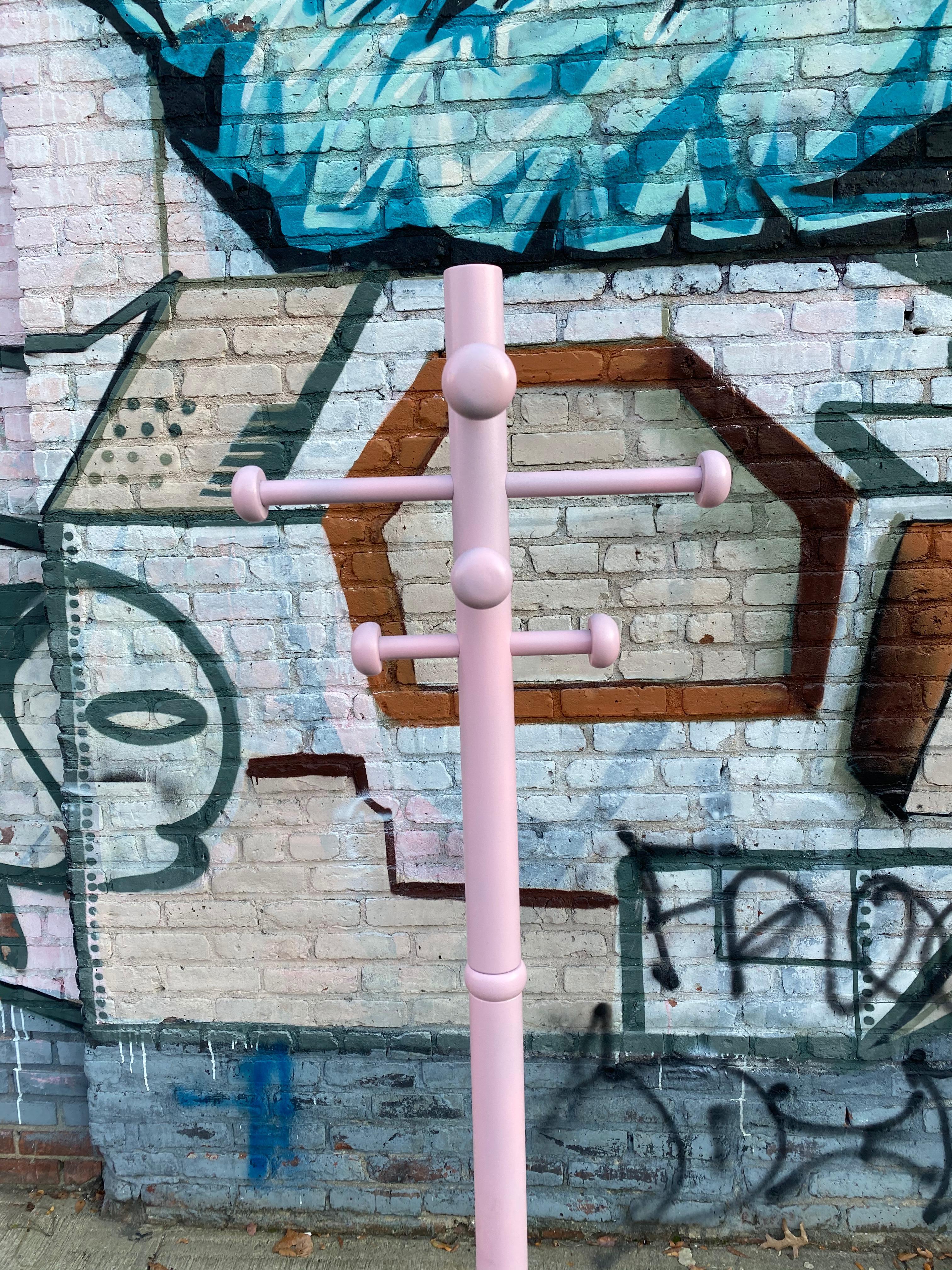 Modern atomic style coat rack or coat tree in pink. Bright even color makes a pop of color in a functional piece of furniture to hold jackets, scarves, hats, umbrellas, etc. Solid wood construction and to hang 8 or more items. Recoated in millennial