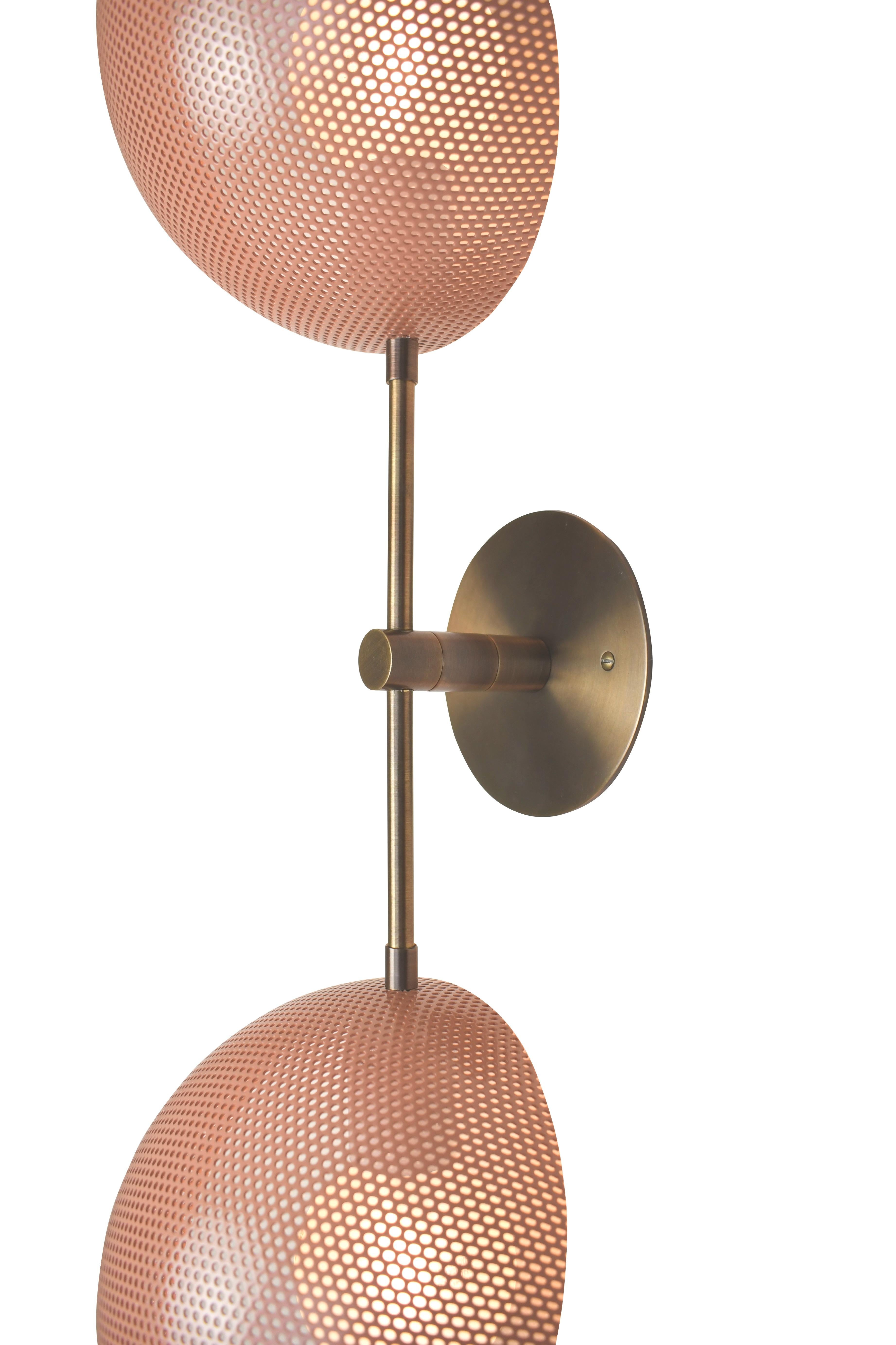 The Axial sconce conveys a strong modern design defined by balance and equilibrium. Axial features two bowl-shaped shades fabricated of spun metal mesh, tilted at an angle, mimicking the axial tilt of the planets in orbit. This line, designed in