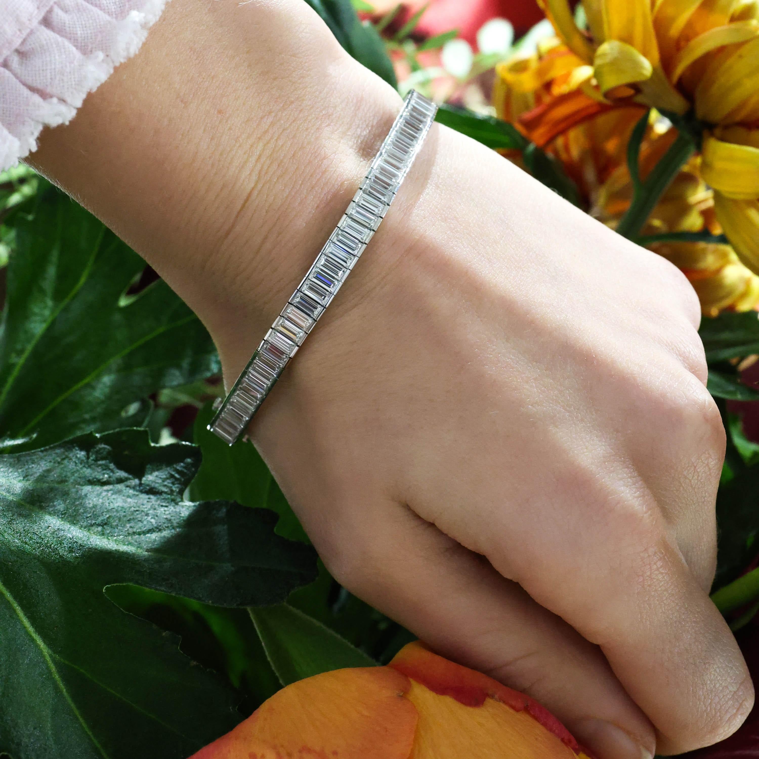 Bracelet moderne en diamant et platine, serti en canal d'une seule rangée de diamants de taille baguette, dans des maillons articulés individuellement, avec des côtés ouverts et polis, avec un fermoir en forme de boîte et de languette, avec un cran