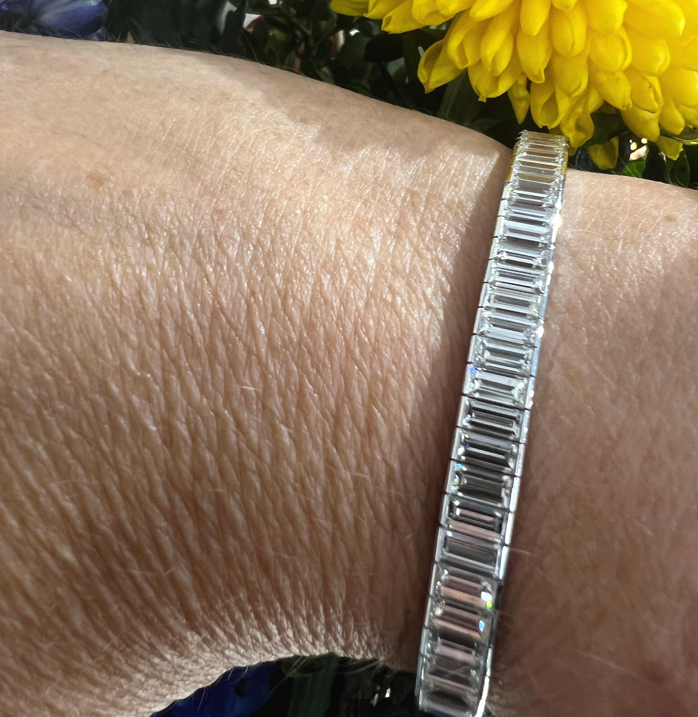 A modern baguette diamond bracelet, with 68, baguette-cut diamonds, with a total weight of 16.23 carats, in channel settings, with individually hinged links, with open sides and a box and tongue clasp, with a safety clasp, mounted in platinum.