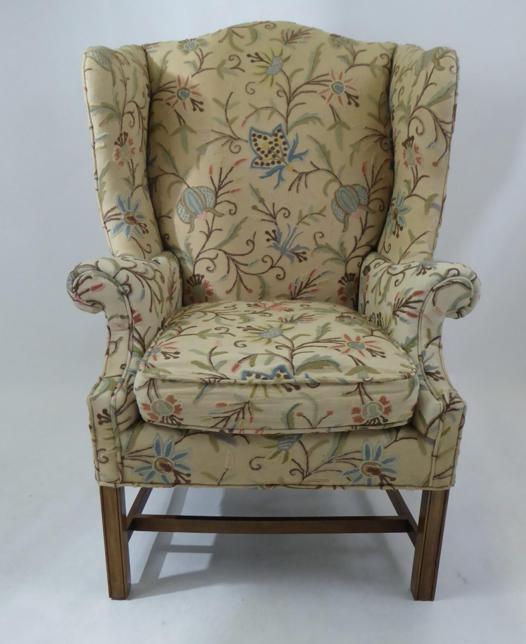 A wonderful 1950s era Baker Chippendale style wingback in a multicolor Crewel stitched fabric. Lovely floral motif in the crewel stitching, beautiful dark wood legs, great deep wings and curves. Some scratched fabric/ worn area on back left side