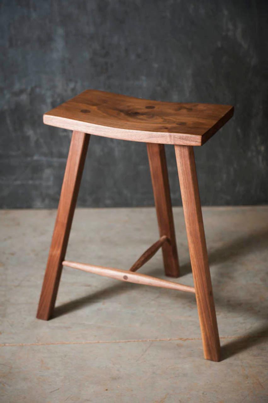 This classic walnut stool is sturdy, comfortable, and great looking. Made from Walnut using traditional mortise and tenon construction. The scooped seat is 16” wide x 10”: deep. We make these stools from black walnut and use the very best selection