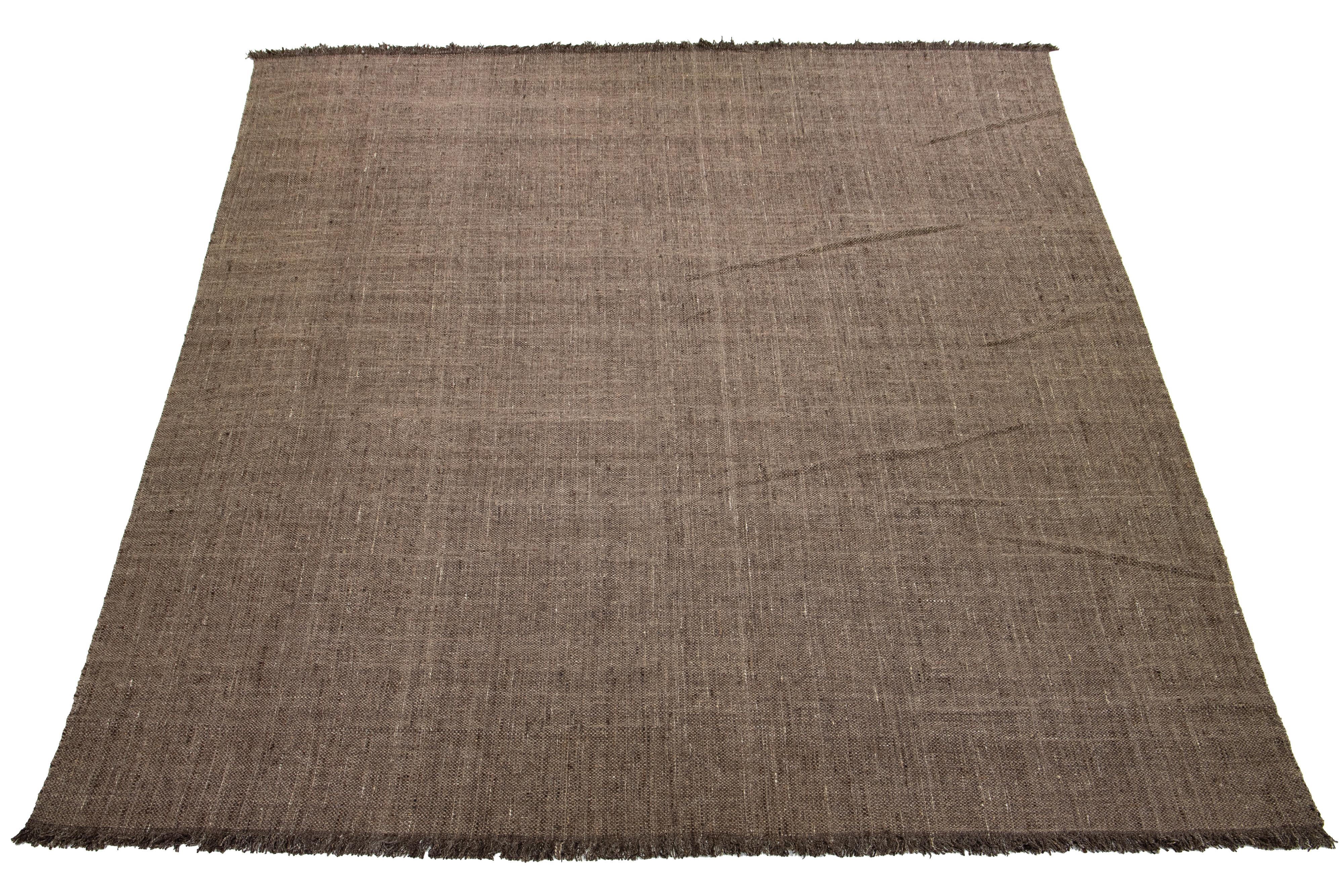 Dieser Teppich besticht durch sein modernes, organisches Korbflechtmuster aus hochwertiger Wolle. Die braune Farbpalette wird durch eine fesselnde Ästhetik ergänzt, die wunderbar mit der Natur harmoniert.

Dieser Teppich misst 12' x 15