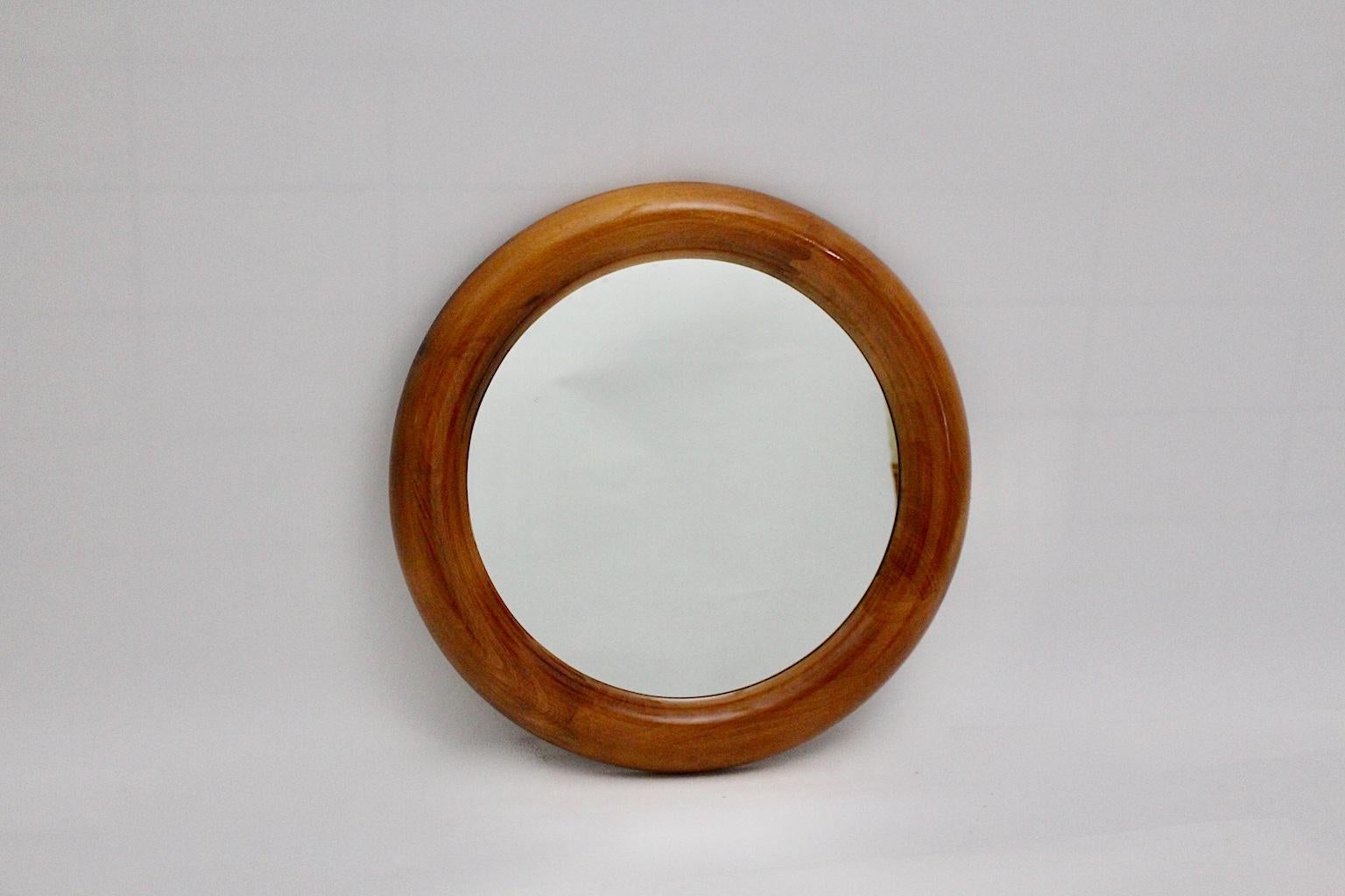 Miroir mural vintage moderne de forme ronde en hêtre laqué naturel et verre miroir.
Le miroir mural présente un magnifique ton de couleur chaude et vive, très similaire à celui du bois de cerisier, qui révèle une chaleur et une profondeur