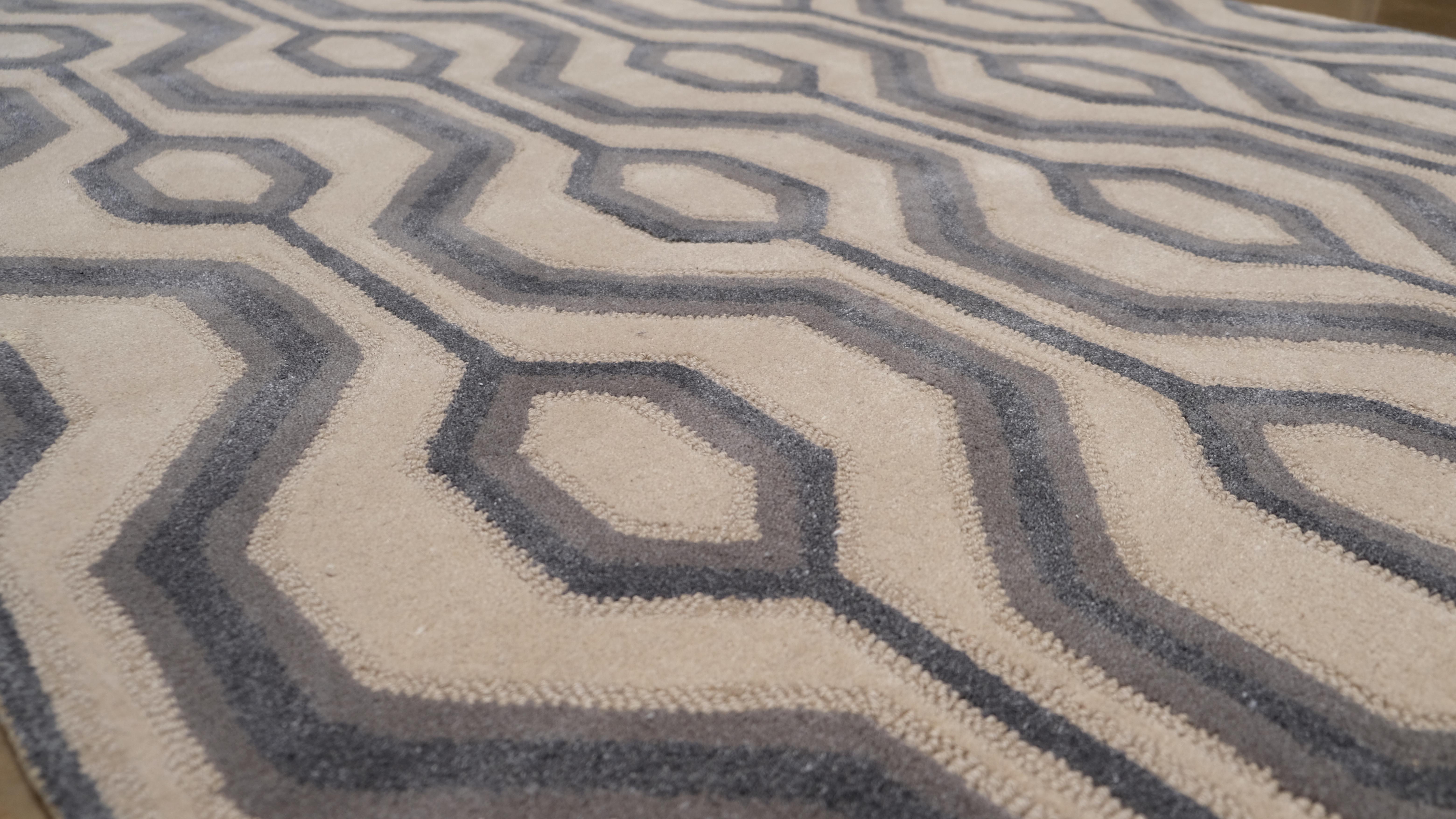 This  wool rug showcases a geometric modern pattern featuring interlocking hexagons in a striking beige and grey color palette. The sharp contrast and contemporary design make it a perfect statement piece for modern, mid-century, or eclectic