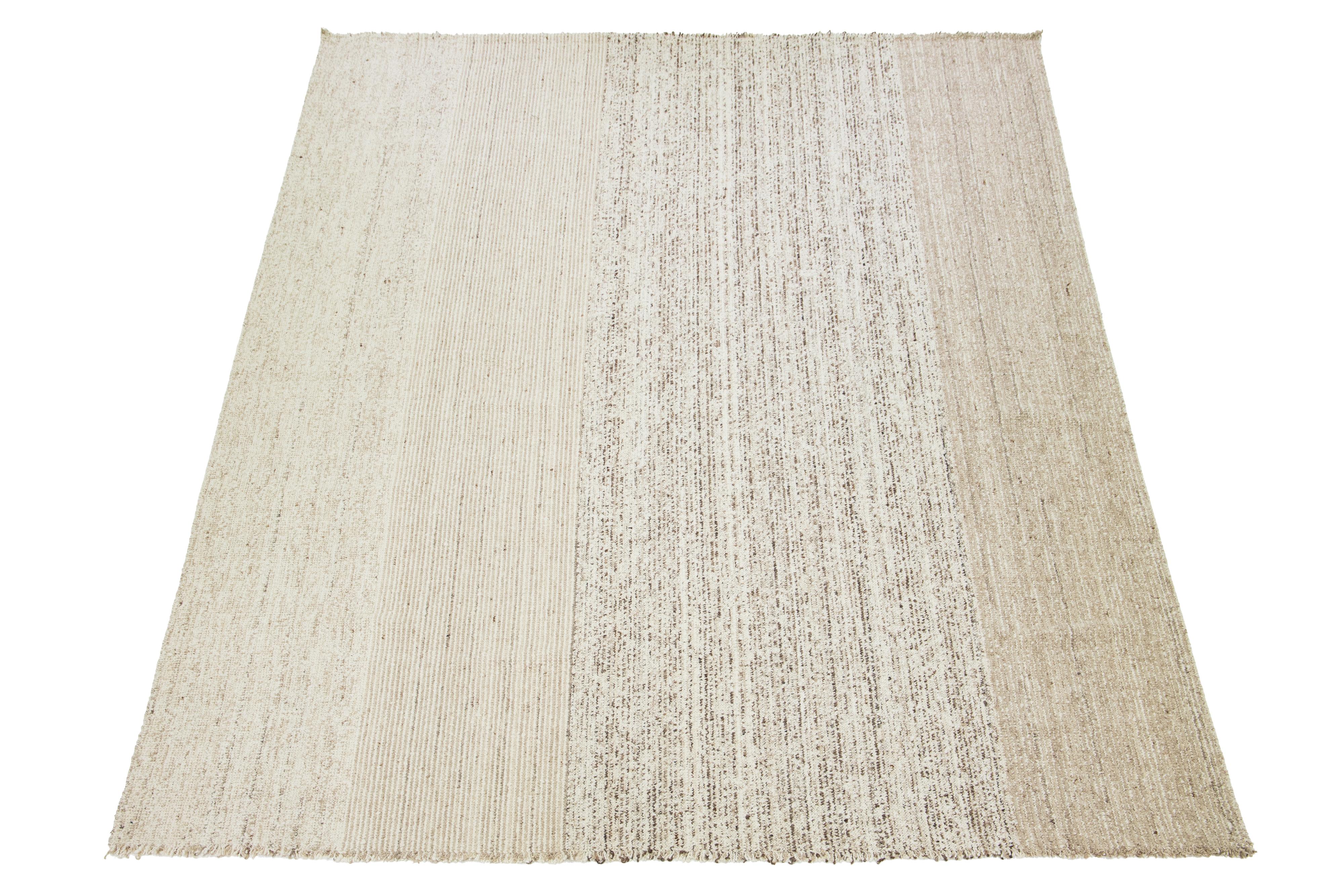 Un tappeto kilim contemporaneo a trama piatta presenta un campo beige con accenti marroni in un disegno geometrico all-over.

Questo tappeto misura 12'1