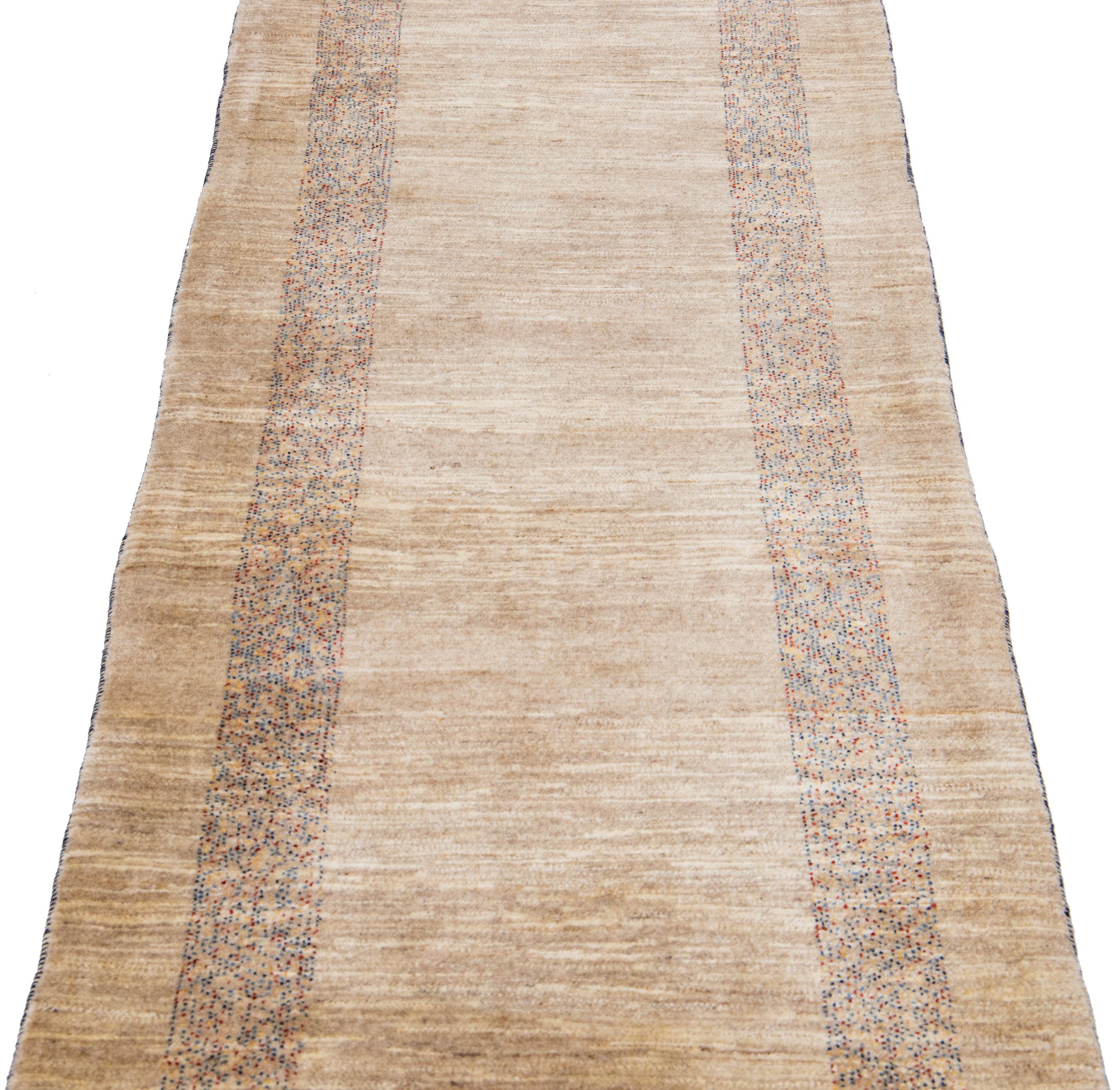 Beautiful modern Gabbeh-style hand-woven wool runner with a beige color field. This piece has blue and red accents in a gorgeous geometric design.

This rug measures: 2'8