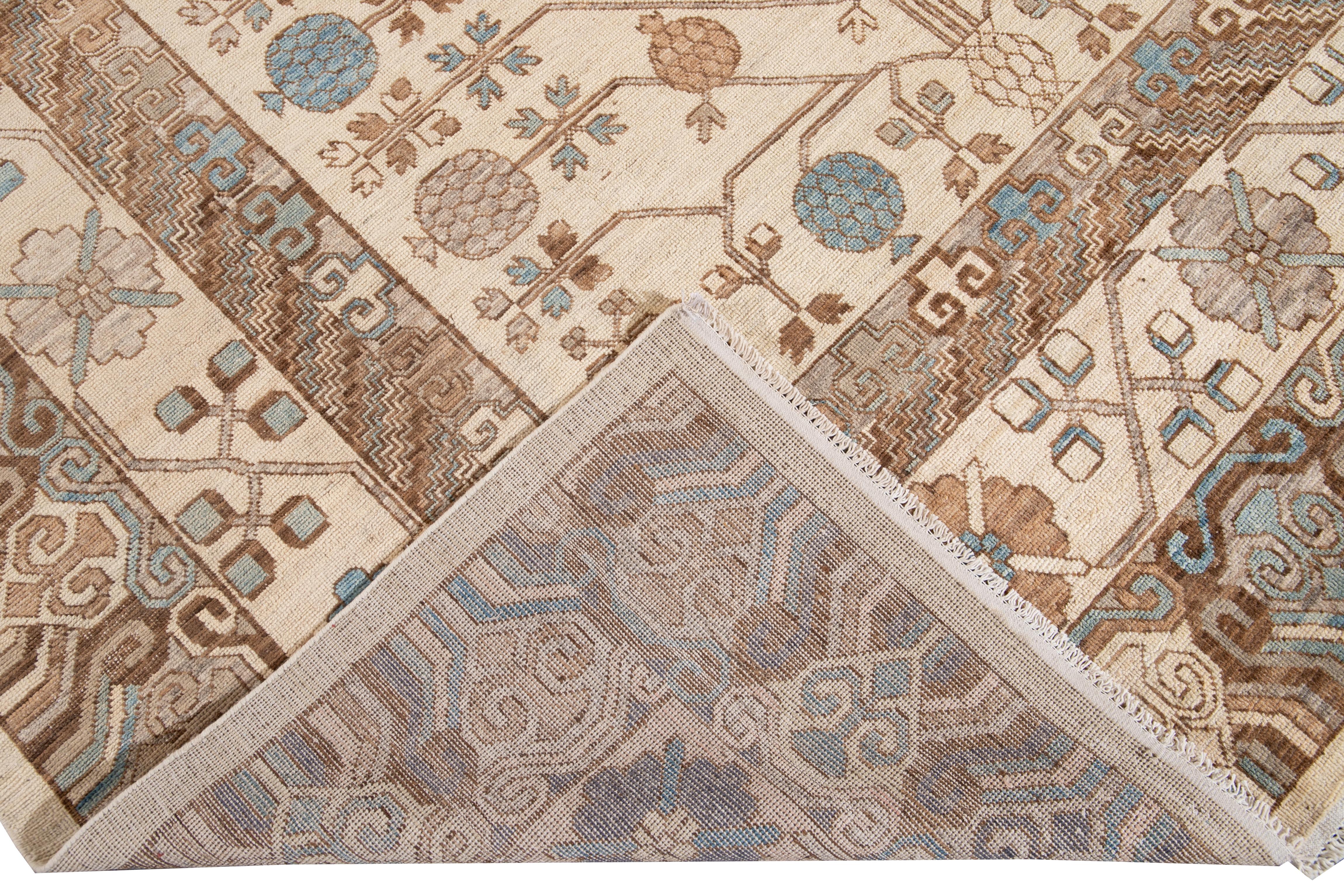 Beautiful modern Khotan style hand knotted wool rug beige field. This Khotan-style rug has a beautifully designed frame and accent of blue, beige, and brown in a gorgeous all-over geometric floral design.

This rug measures 8' 1