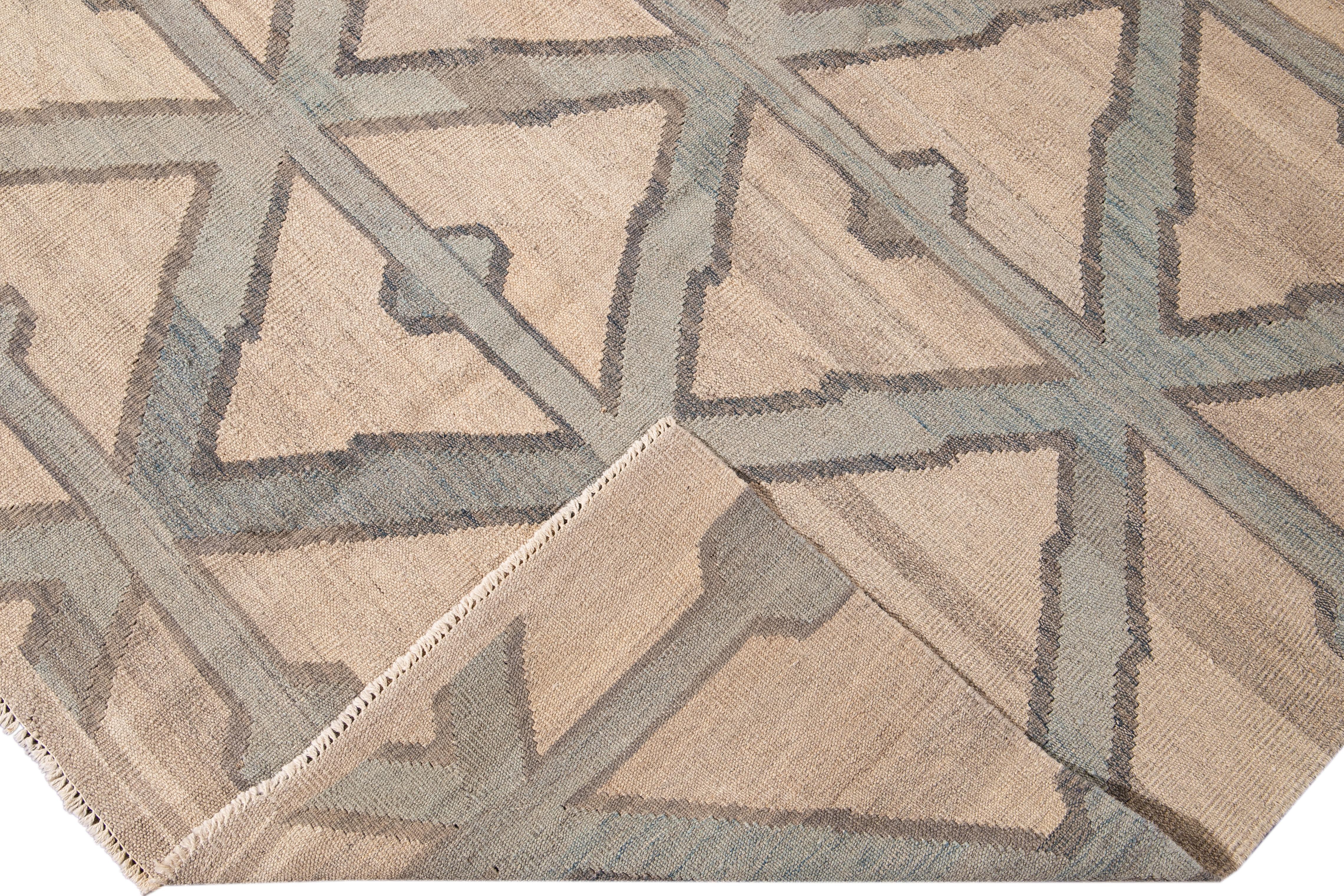 Beautiful modern Kilim flat-weave wool rug with a beige field. This piece of art has green and gray accents in a gorgeous geometric diamond pattern design.

This rug measures: 7'10