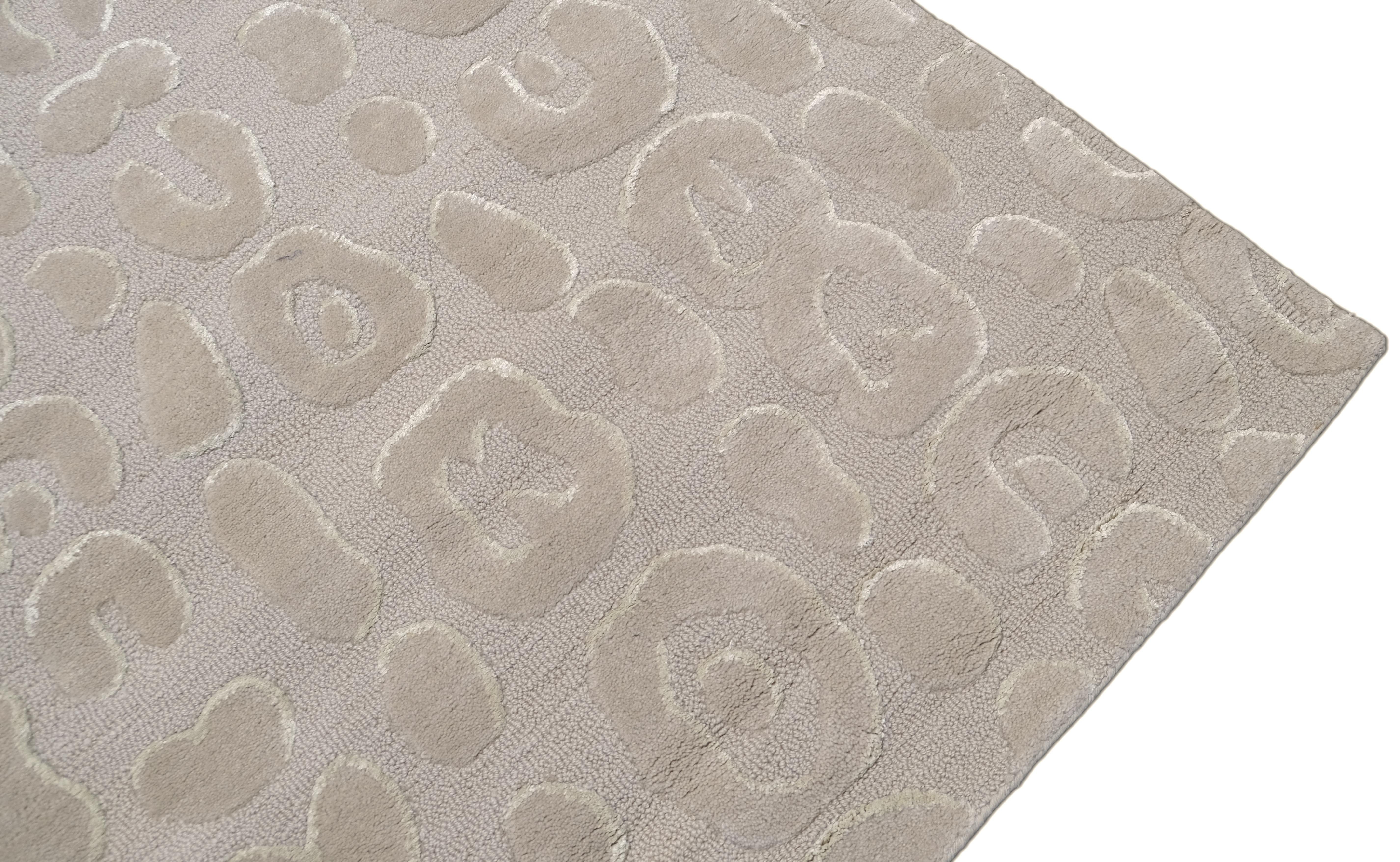 Ce tapis en laine présente un mélange sophistiqué de luxe moderne et d'artisanat complexe. Doté d'un motif abstrait gaufré de formes organiques, ce tapis crée un jeu dynamique de textures, ce qui en fait une pièce marquante pour les intérieurs