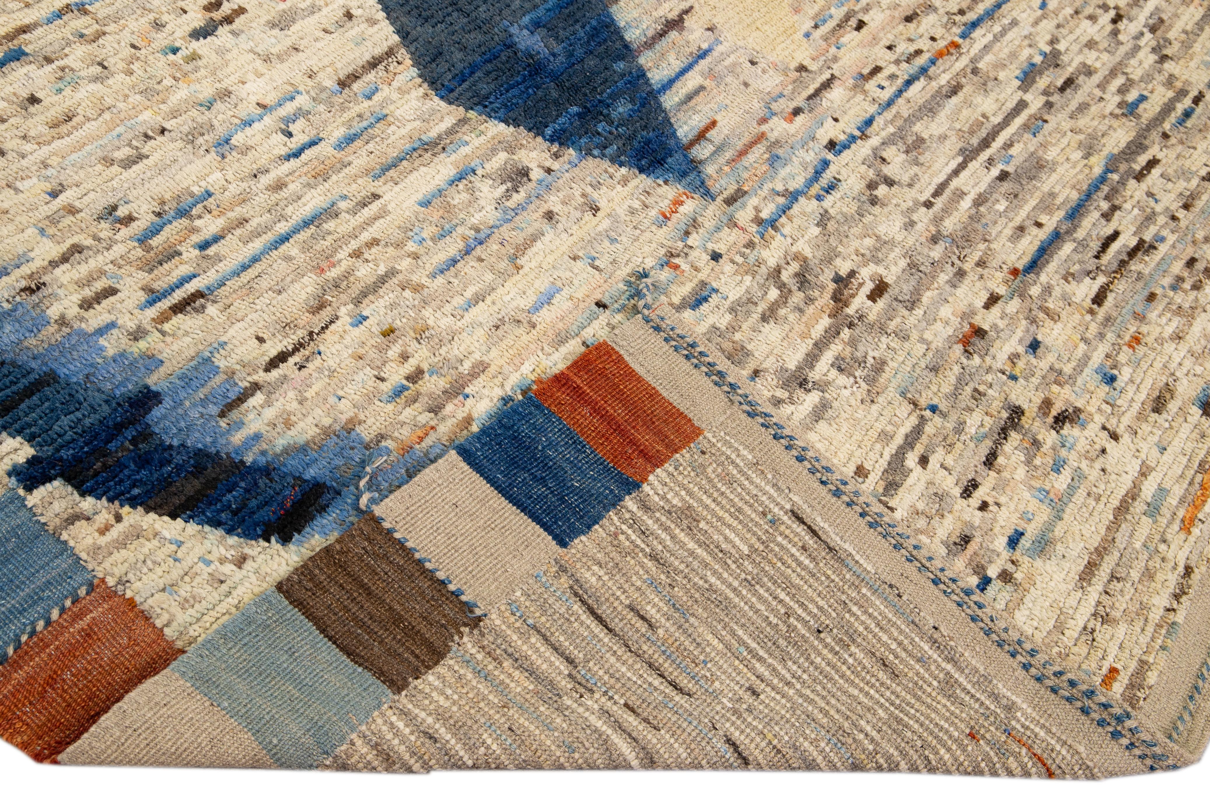 Beautiful Moroccan style handmade wool rug with a beige field. This Modern rug has blue and orange accents and beige-blue braid fringes featuring a gorgeous all-over geometric boho design.

This rug measures: 8'9