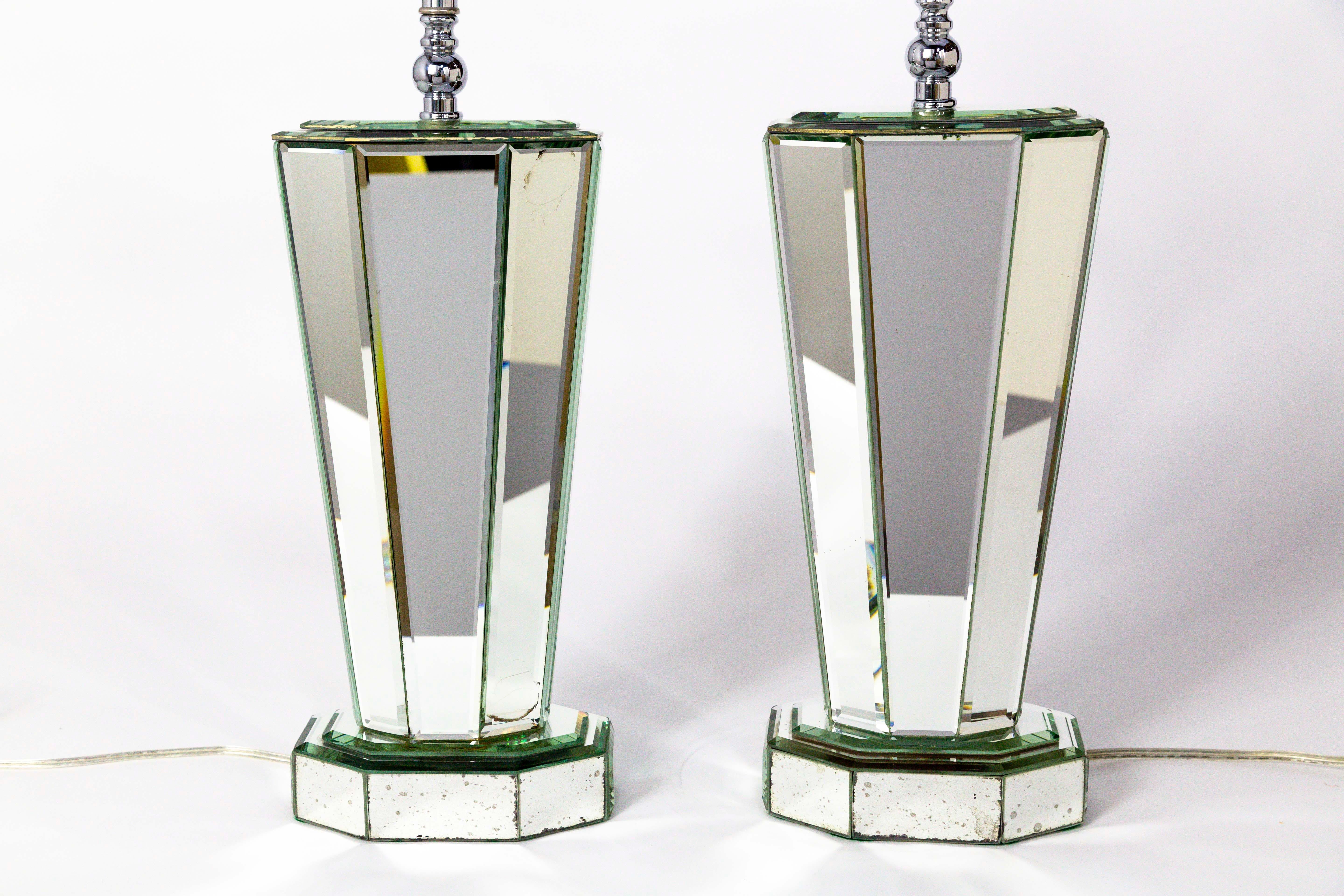 A pair of striking, modern, beveled mirror table lamps that create beautiful light reflections. A late 1970s, streamlined design; faceted, narrow, 8-sided, column-esque shape that tapers slightly at the mirror paneled base. Topped with large, Deco