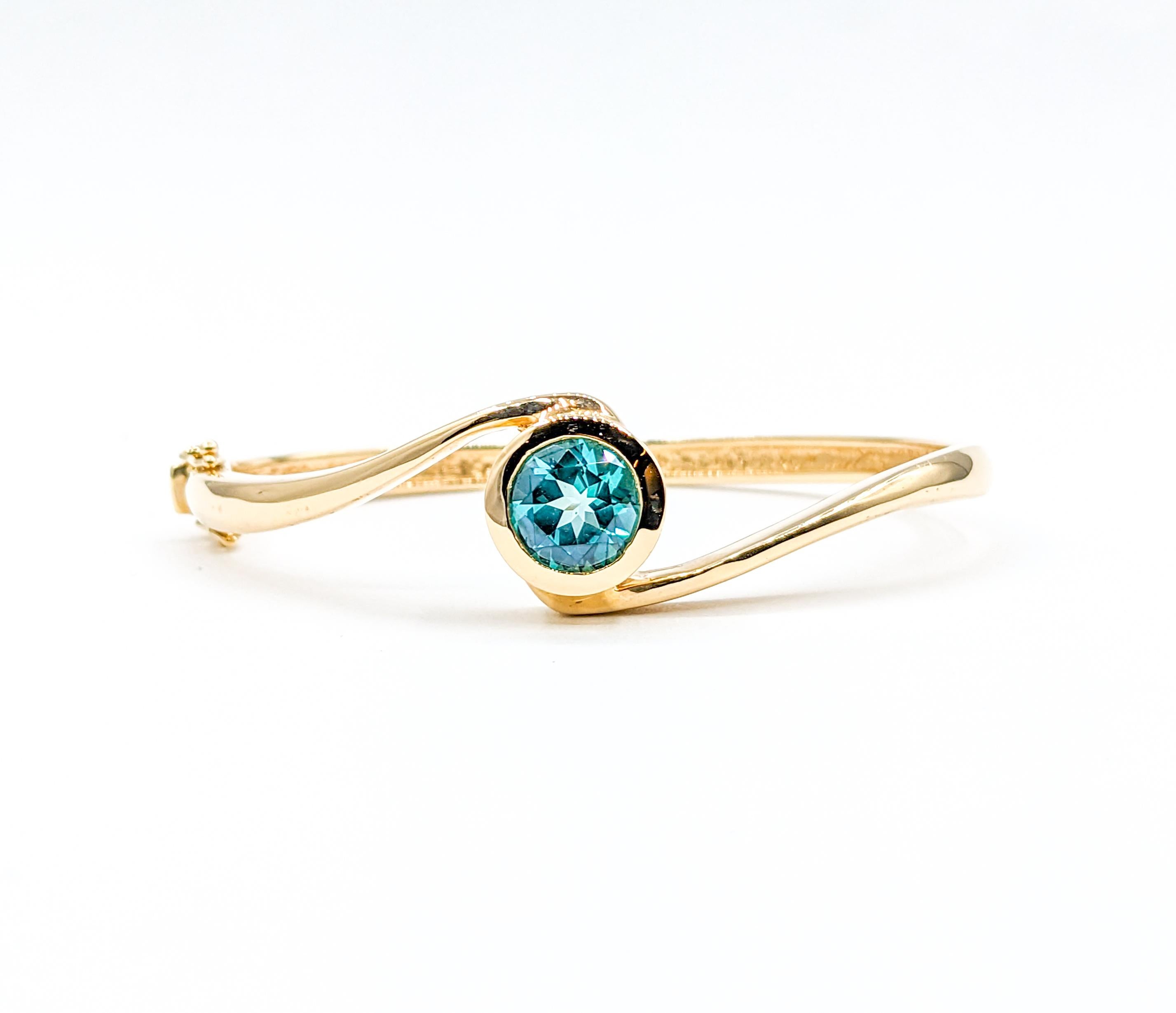 Modern Bezel Set Blue Topaz Hinge Bangle Bracelet in Yellow Gold

Introducing this exquisite bracelet bangle, a magnificent piece of jewelry skillfully crafted in 14k yellow gold and adorned with a captivating 9mm round blue topaz. The topaz's