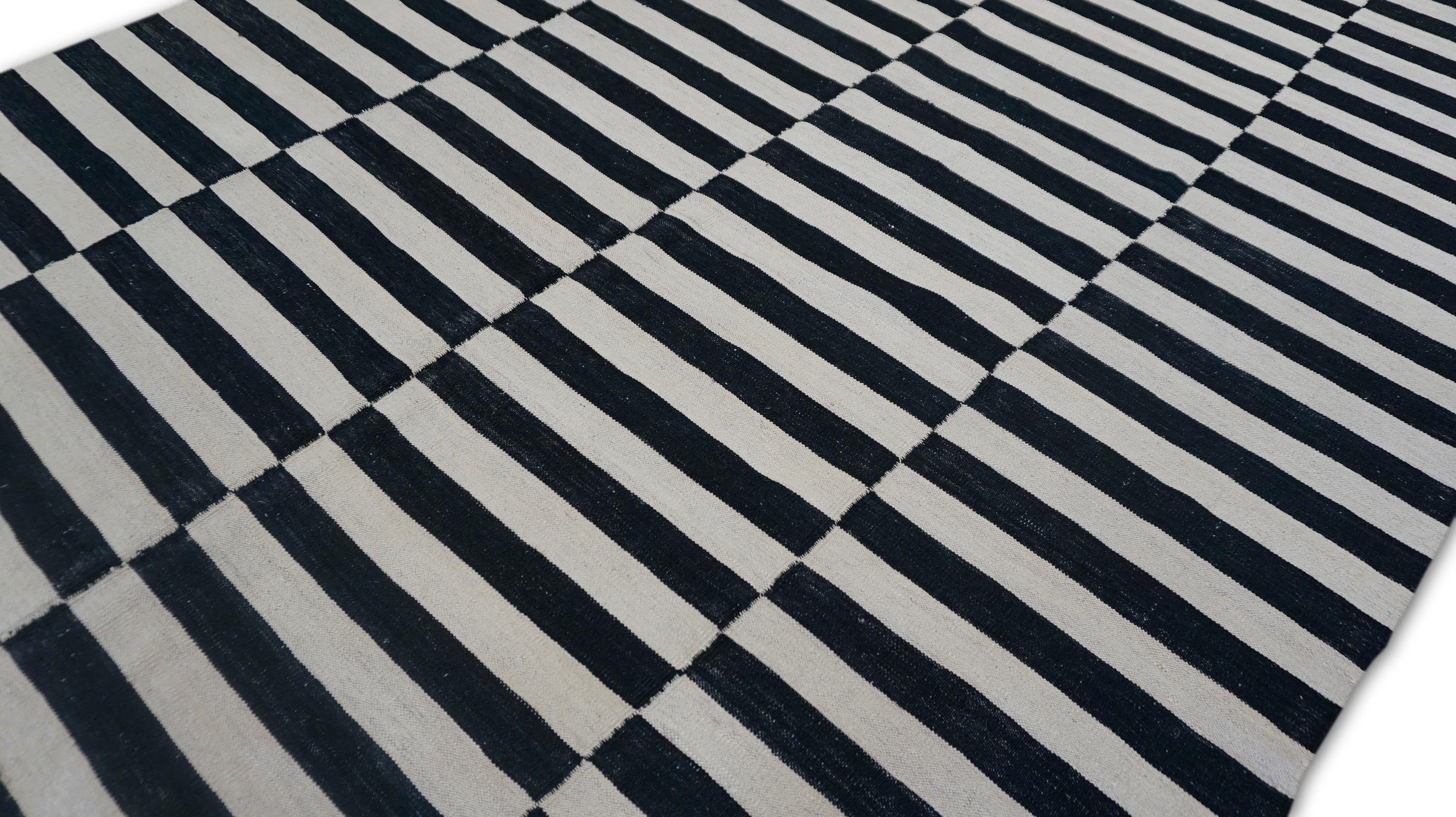 Dieser zeitgenössische, handgewebte Wollteppich ist ein kühnes und grafisches Statement, das durch seine fachmännische Verarbeitung minimalistische Eleganz mit einer kontrastreichen optischen Wirkung verkörpert. Der Teppich zeigt abwechselnd
