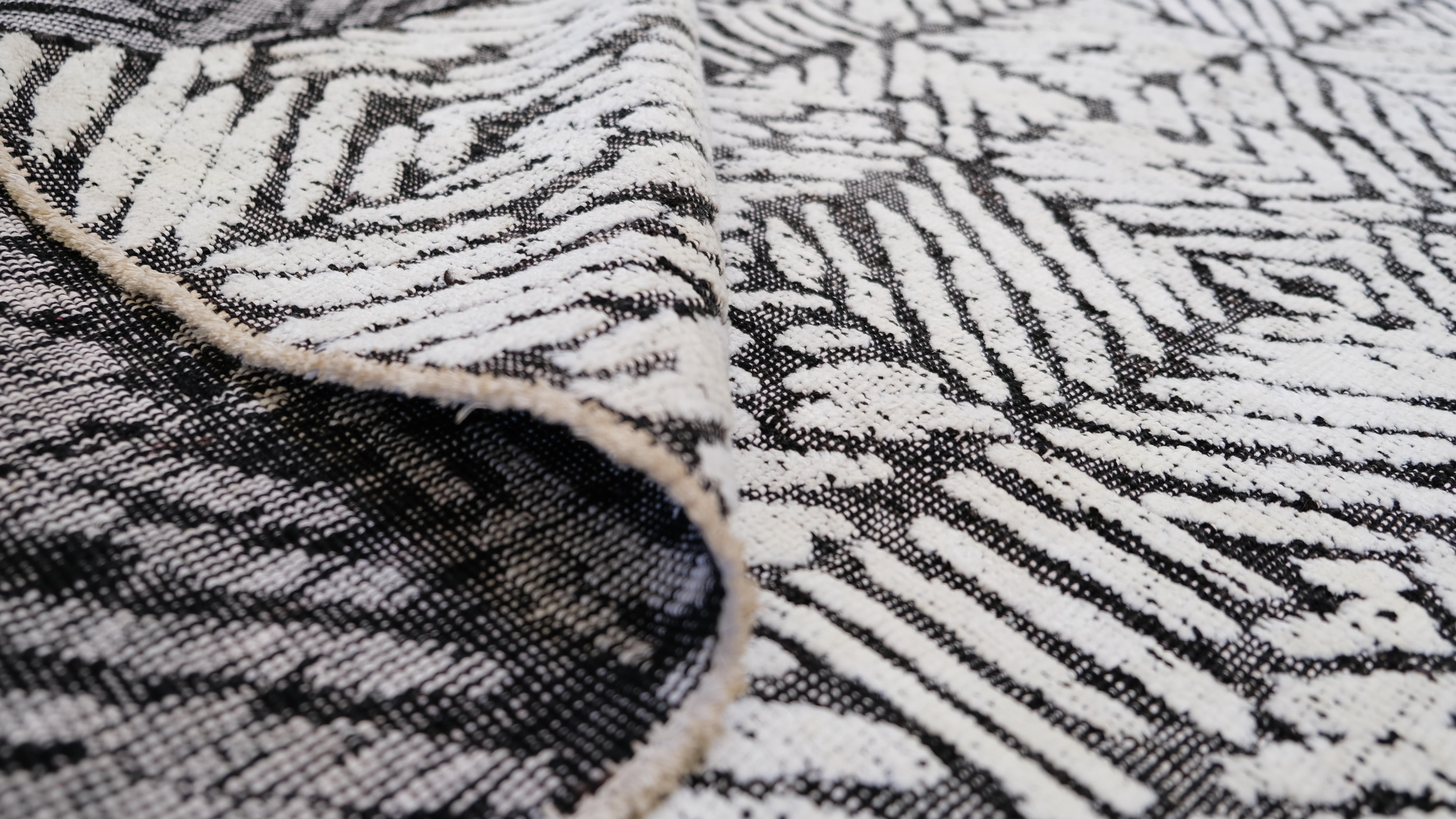 Ce tapis noué à la main de Whiting présente un motif géométrique audacieux en noir et blanc qui crée un effet d'optique captivant. Le motif complexe, composé de formes dynamiques qui se chevauchent, apporte une touche contemporaine à tout intérieur,
