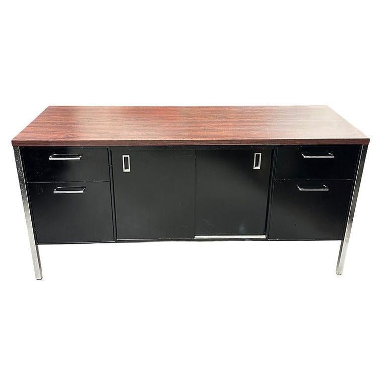 Credenza vintage moderna in acciaio smaltato nero con gambe cromate e piano in laminato di noce. Questa credenza è stata realizzata da Steelcase e si ispira ai design di Florence Knoll, come dimostrano le eleganti gambe cromate, la forma geometrica