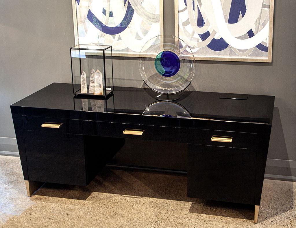 Modern black desk credenza by Jacques Garcia Baker Rachmaninov. Featuring unique modern styling, finished in a black hand polished look. Complemented with sleek brass handles and metal leaf foot accents.

Price includes complimentary curb side