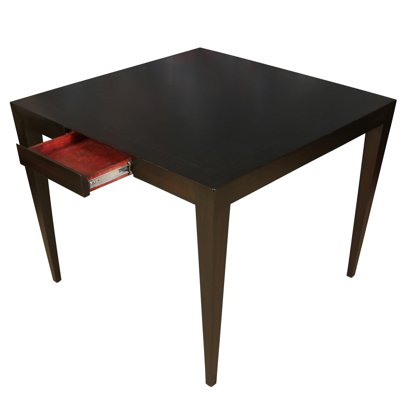 A modern ebonized games table with a single drawer.  The parsons style black table has modern tapered legs and an etched border on the top perimeter.