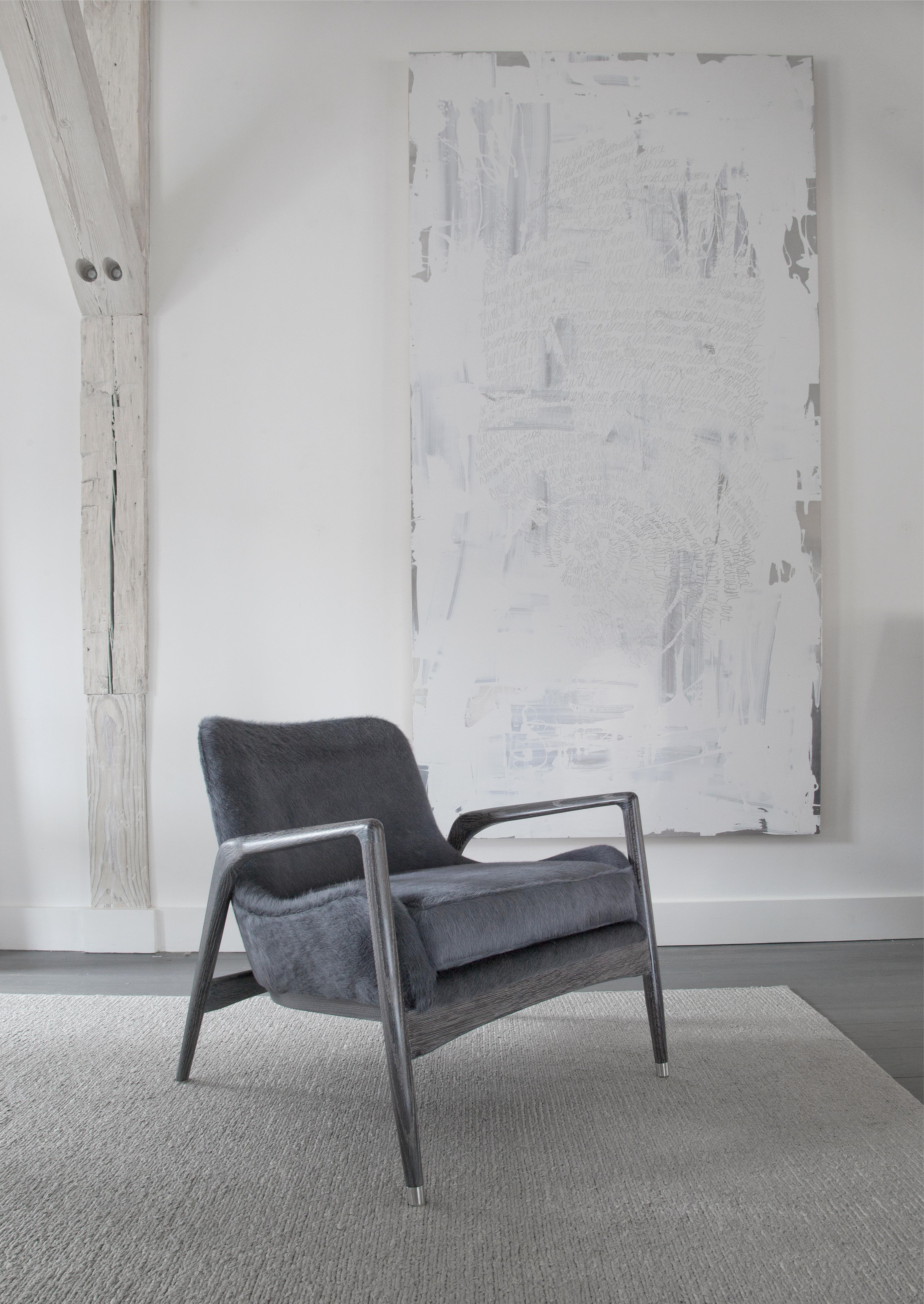 An elegant blackened oak armchair upholstered in black hide evokes clean mid-century lines while providing a relaxing seating experience. The striking hide upholstery provides textural interest as well as comfort. The armchair is also offered in