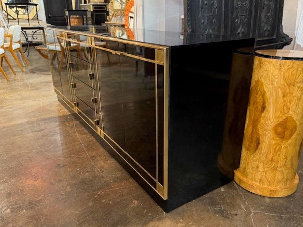 The modern black lacquer and brass sideboard after Pierre Cardin features a sleek design. . The combination of black lacquer and brass detailing gives it a contemporary and luxurious look, perfect for showcasing in a living room or dining area. This