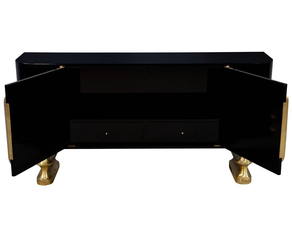Modern polished black lacquer sideboard credenza. Featuring curved sides with slotted brass hardware, sitting on two unique one of a kind flowing brass bases.
Complimentary curb side delivery included to the continental USA.
