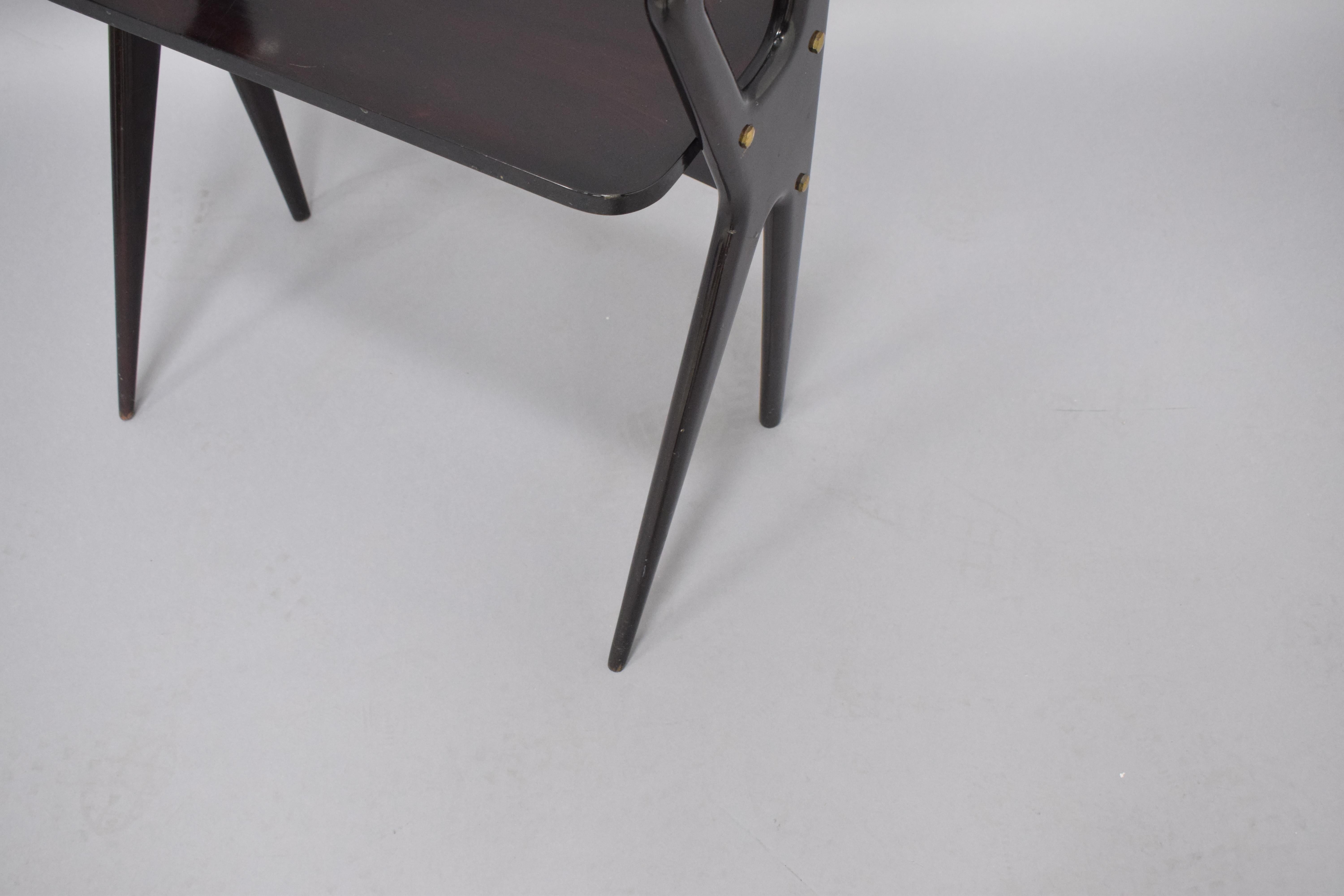 Moderner Beistelltisch und Schreibtisch im Vintage-Stil aus schwarz lackiertem Holz mit Glasplatte, unterer Holzplatte und Messingbeschlägen. Dieses Möbelstück zeigt sowohl gerade als auch konisch zulaufende Beine, ein gängiges Designmerkmal der