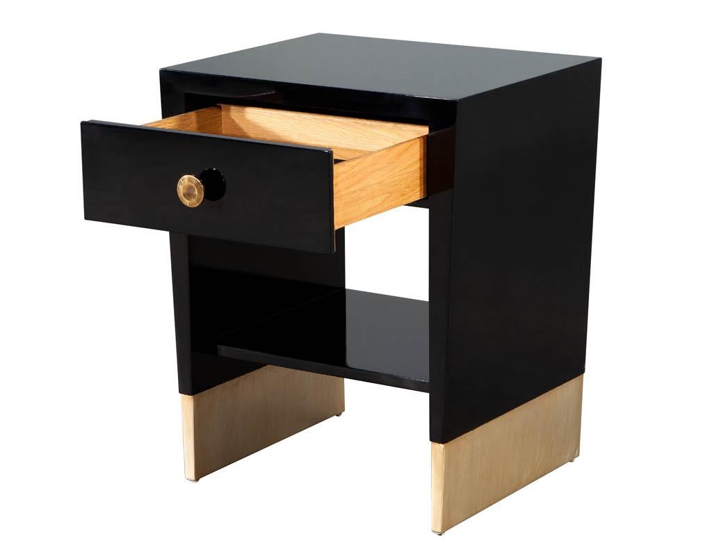 Modern black lacquered end table by Jacques Garcia Baker Furniture. Sleek modern design in hand polished black lacquered finish. Featuring brass plated round hardware and gold leafed base. Matching end table in smaller size available and sold