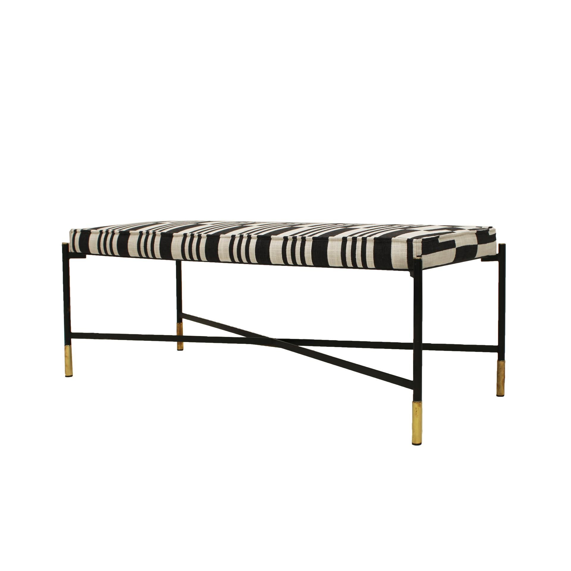 This footstool features a design inspired by Ico Parisi, crafted with a lacquered iron structure in black and brass-sleeved legs. It has been reupholstered in linen fabric with a stylish black and white rectangular print. Combining vintage elegance