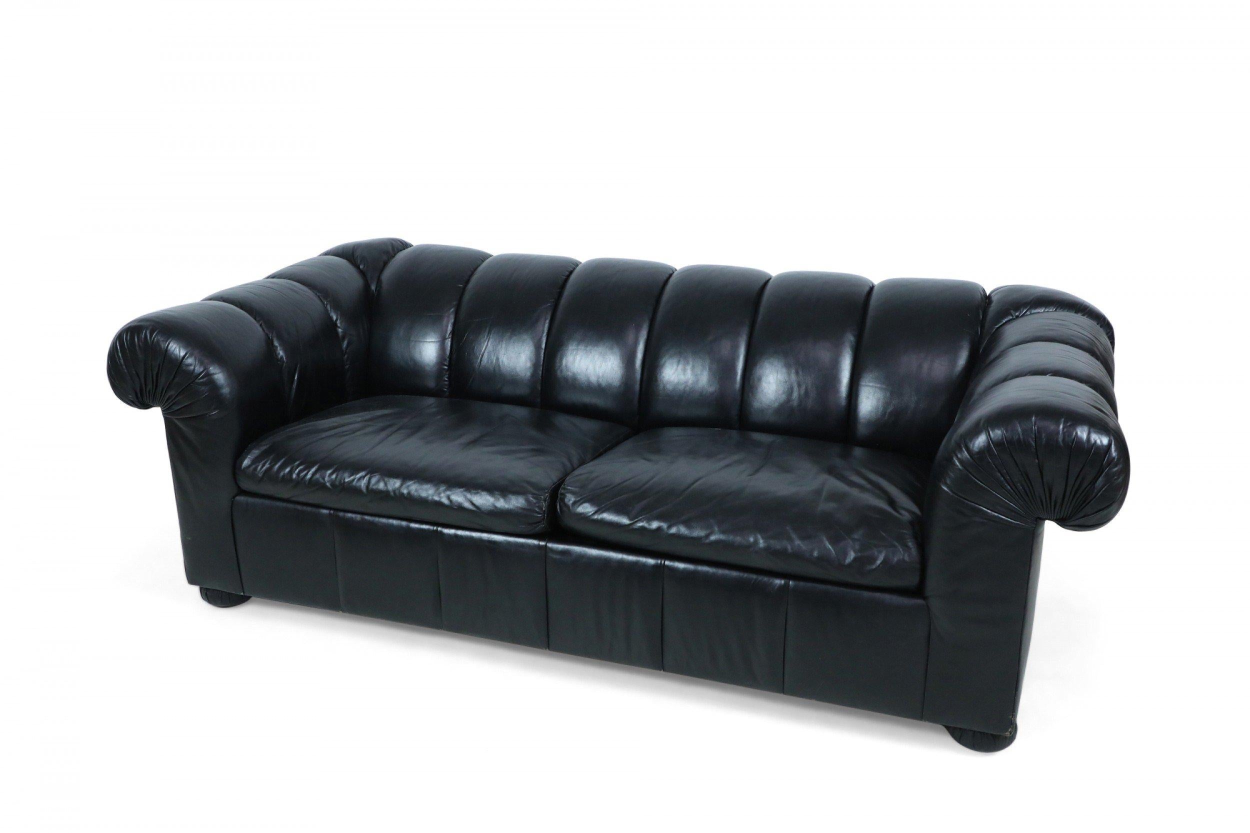 Modernes Chesterfield-Sofa im englischen Stil mit getuftetem schwarzem Leder und ausziehbarem Klappbett unter zwei kanalisierten Sitzpolstern.
 