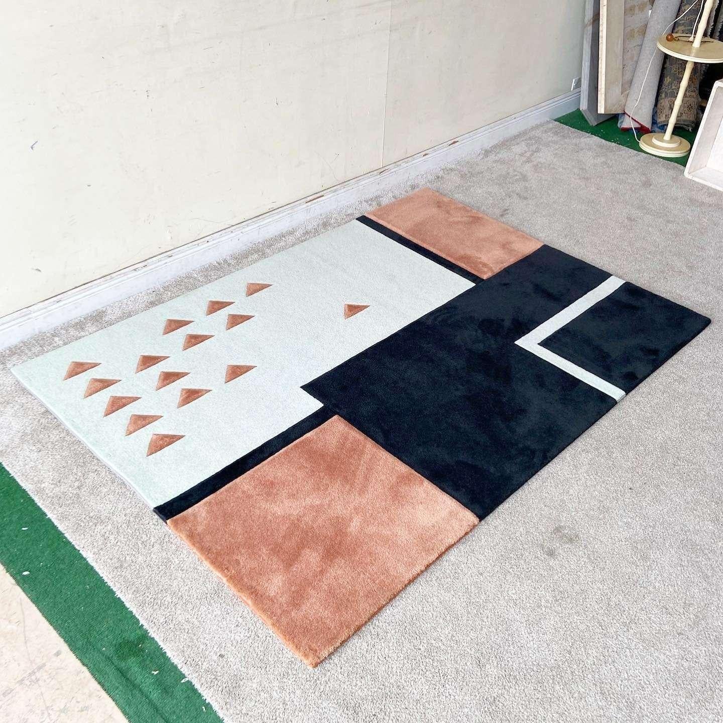Radical vintage modern rectangular area rug. Features black, peach and off-white rectangles partitioned off by black borders. Off-white sections displays several peach triangles.

Rug 8
