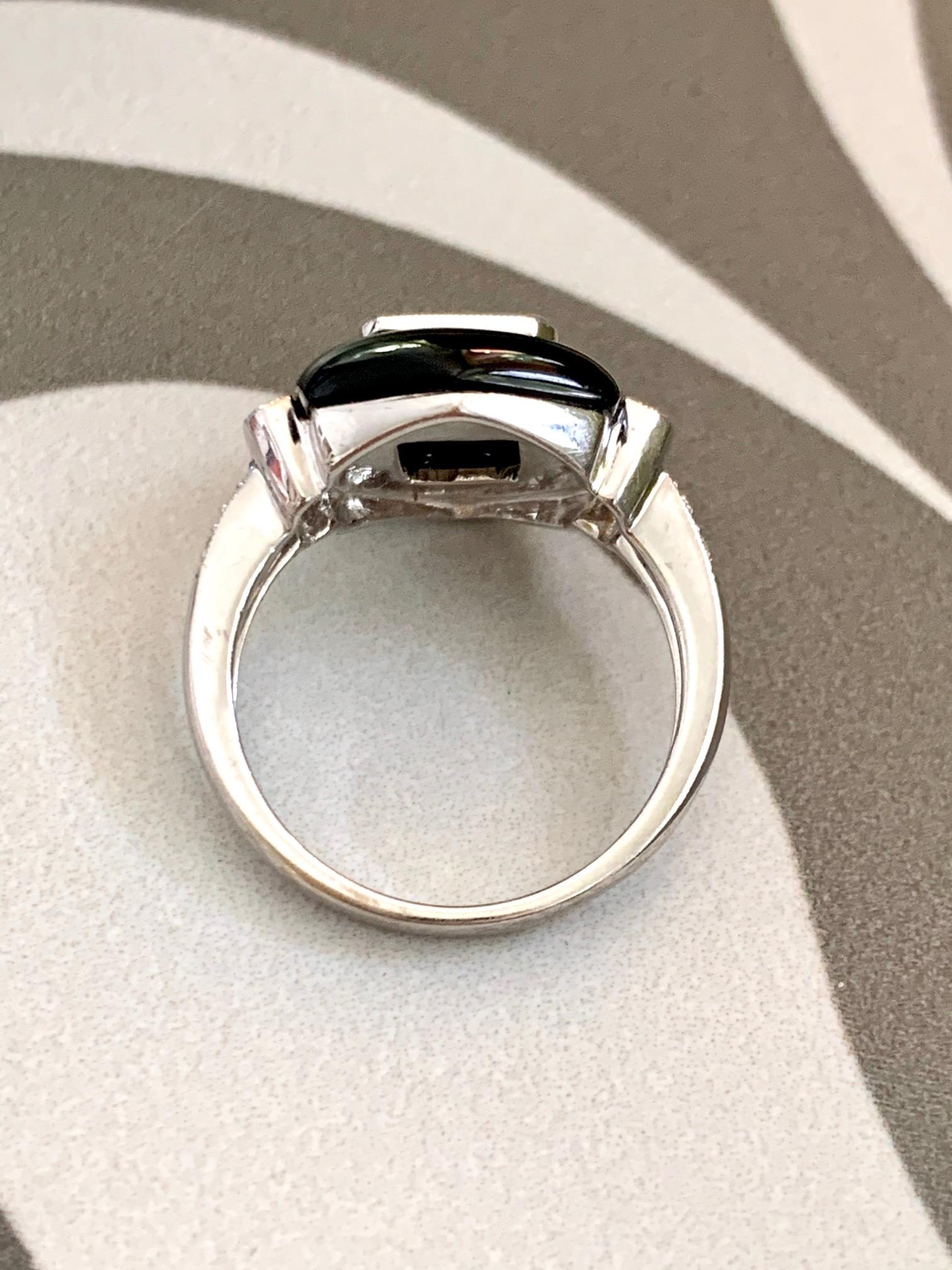 This modern 18 karat white Gold ring features Black Onyx surround four invisible set 3mm princess cut Diamonds and ten brilliant cut 1.4-1.8mm side Diamonds.  The total weight of Diamonds in this ring is approximately .80ctw.  The average grade of