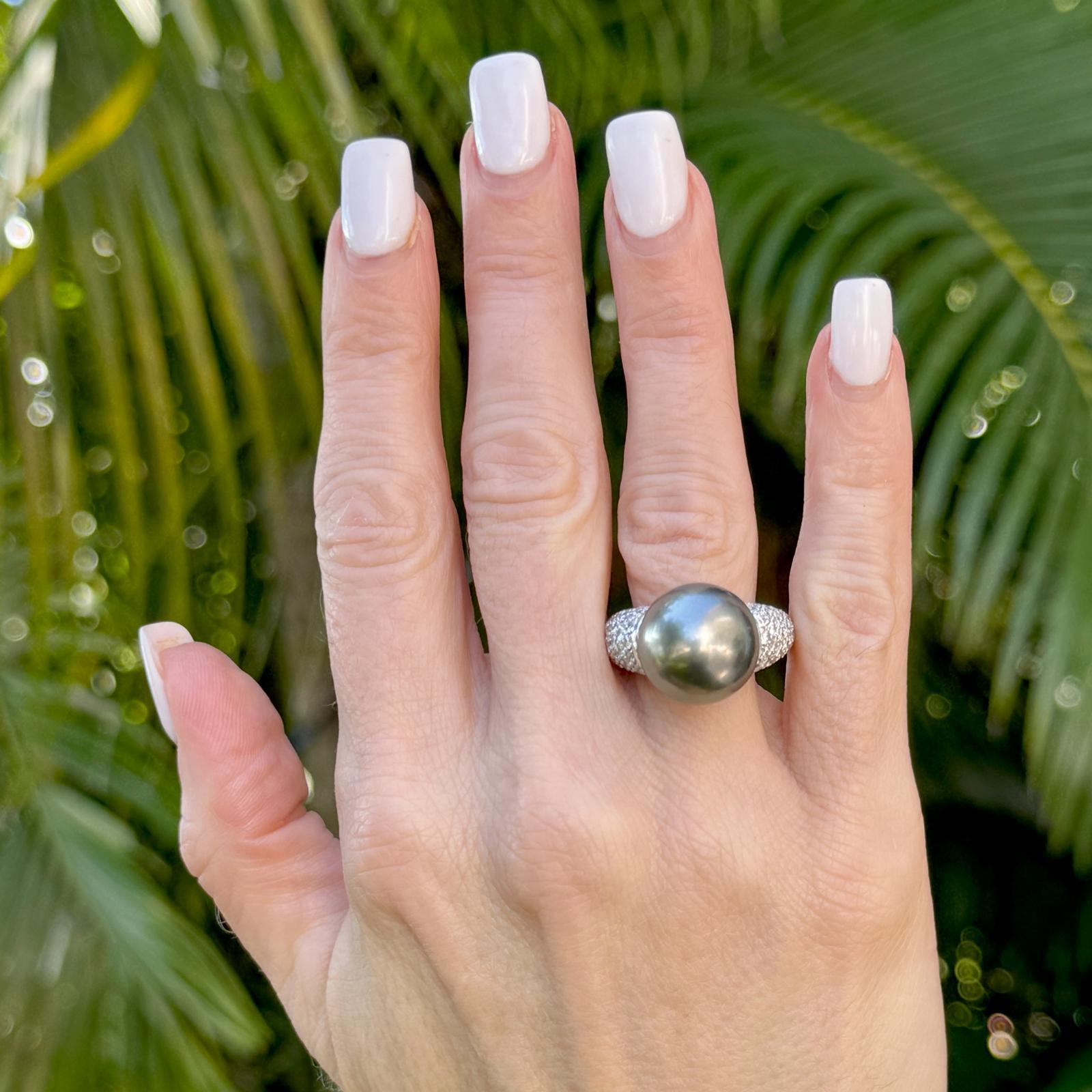 This Platinum Black Tahitian Pearl & Diamond Ring features a stunning 14.5 mm black Tahitian pearl at its center, radiating deep, lustrous hues. Surrounding the pearl are 148 round brilliant-cut diamonds, totaling 3.00 carats with F-G color and VS