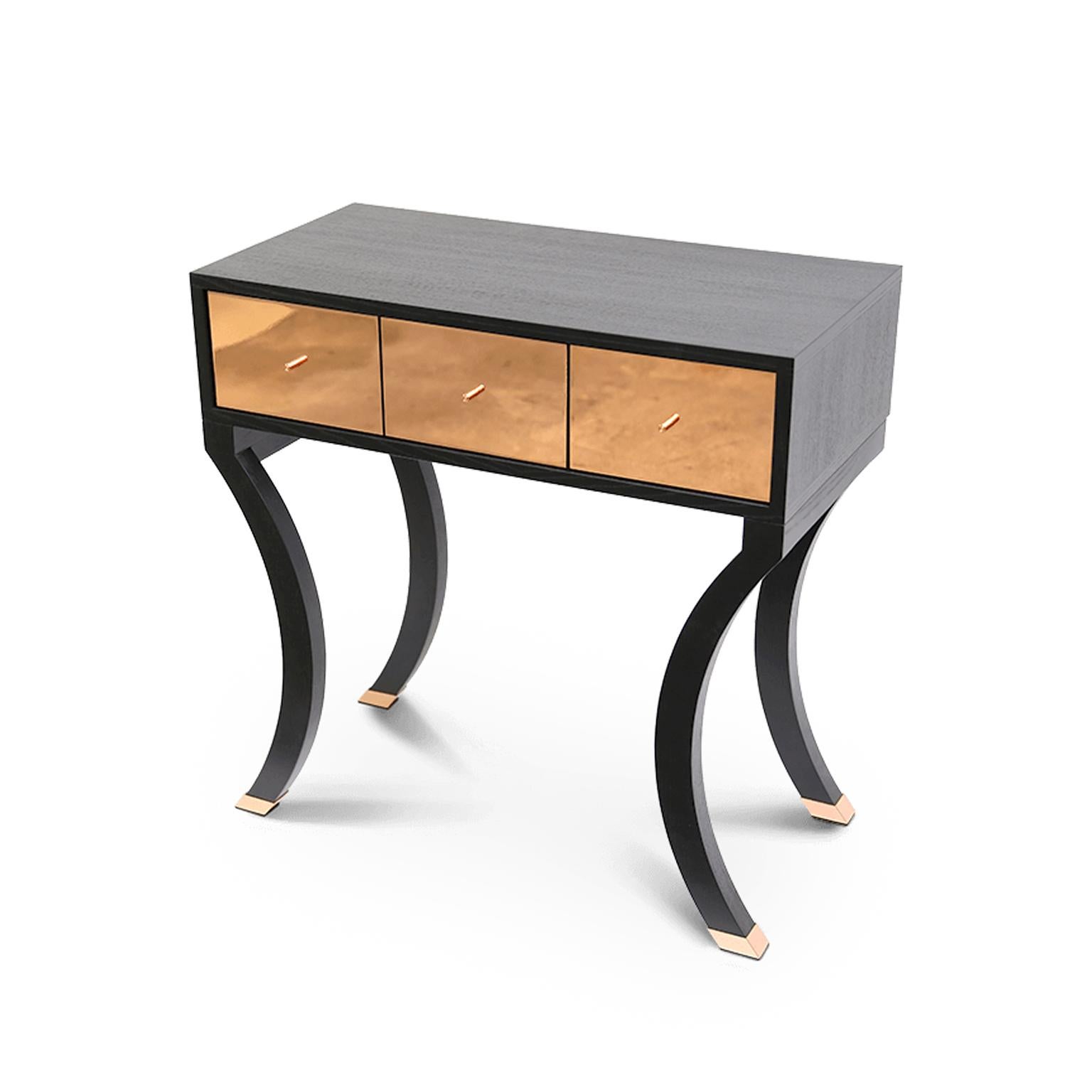 Available in a curated selection of fashionable finishes, this elegant console table is crafted of solid wood, supported by elegant legs. A sleek design complemented with 3 red velvet lined drawers with eye-catching copper pulls offer convenient