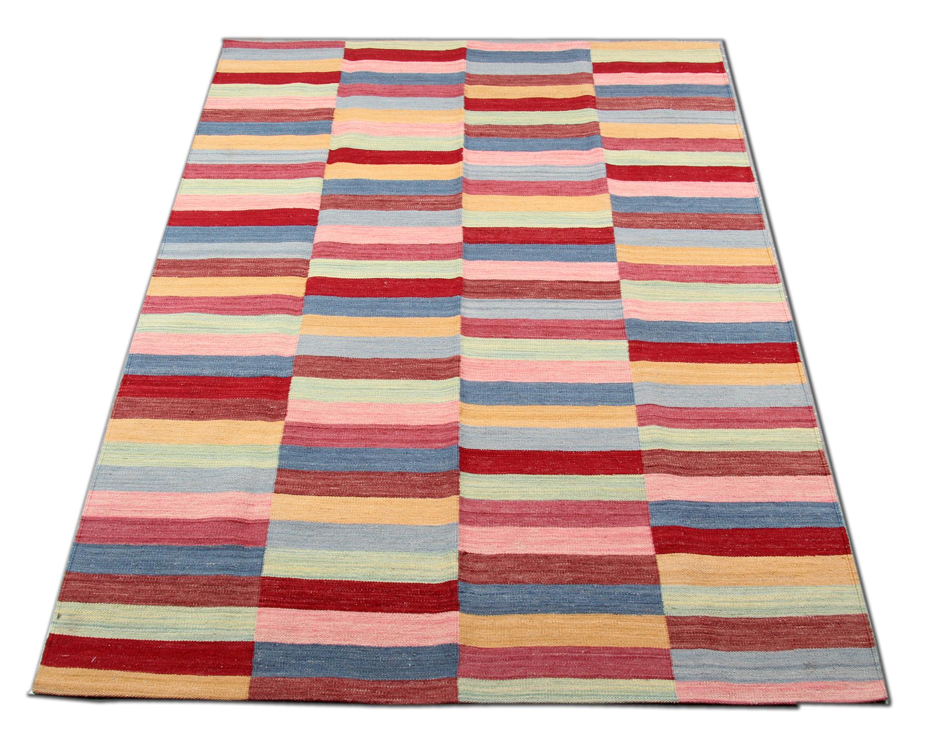 Bold and beautiful this kilim has been woven with a rich block colour pattern in red, green, blue, and pink colours. This striped wool Kilim rug is entirely hand-woven, constructed in Afghanistan using natural fibres and organic dyes. No chemicals