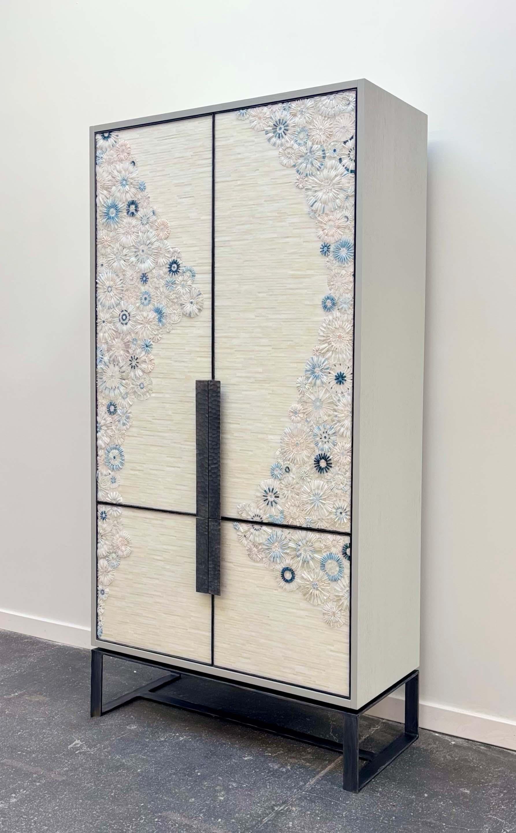 L'armoire moderne Blossom Mosaic d'Ercole Home, est une armoire à 4 portes encadrée de métal étain martelé à la main ainsi que les poignées. Les portes sont ornées de notre motif de mosaïque Blossom taillé à la main dans des couleurs de verre blanc