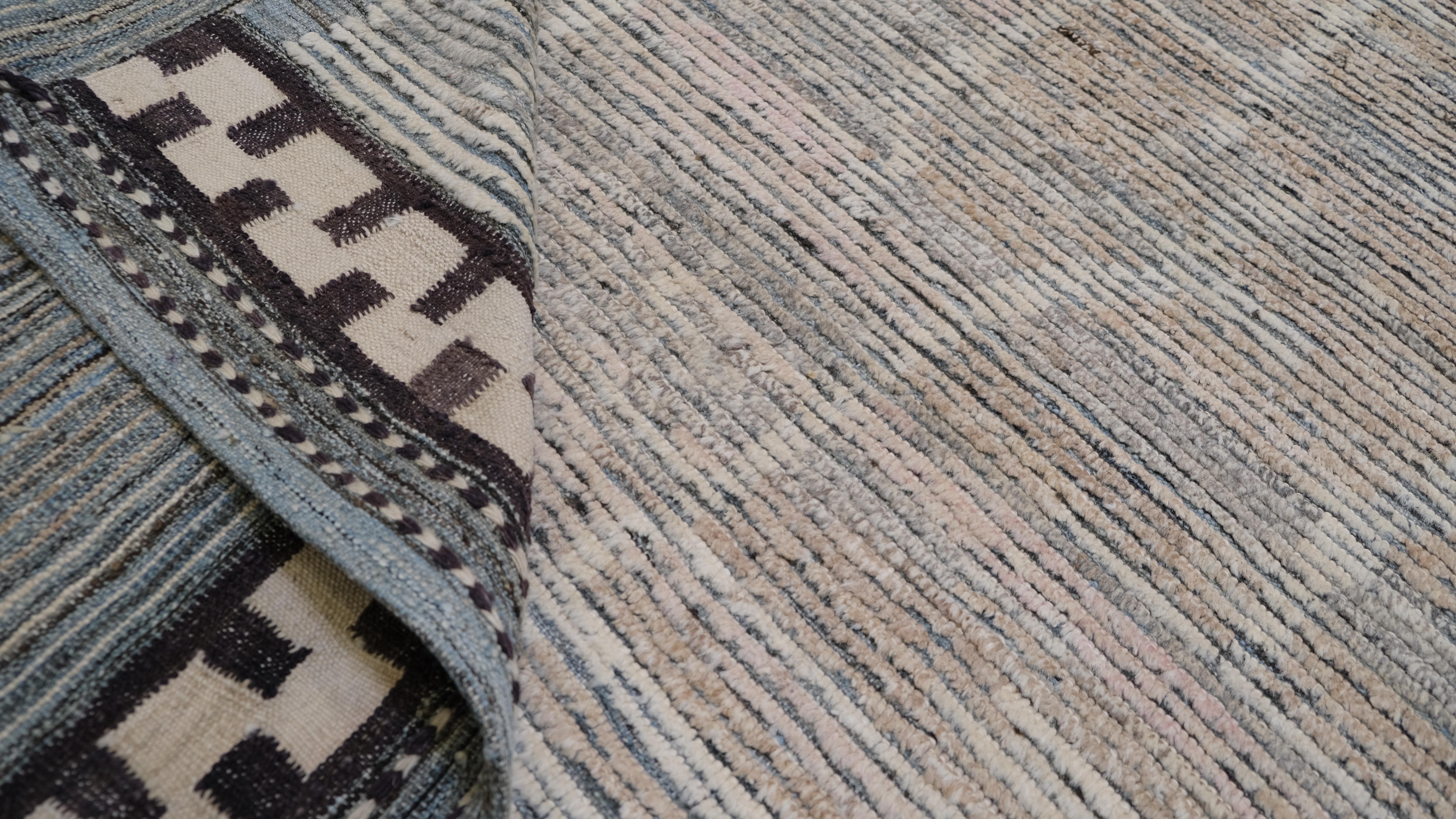 Dieser handgeknüpfte Wollteppich mit zartem Streifenmuster in gedeckten Pastelltönen und auffälligen geometrischen Bordüren wertet Ihren Wohnbereich auf. Die sanften Beige- und Blautöne gehen nahtlos ineinander über und schaffen ein ruhiges und
