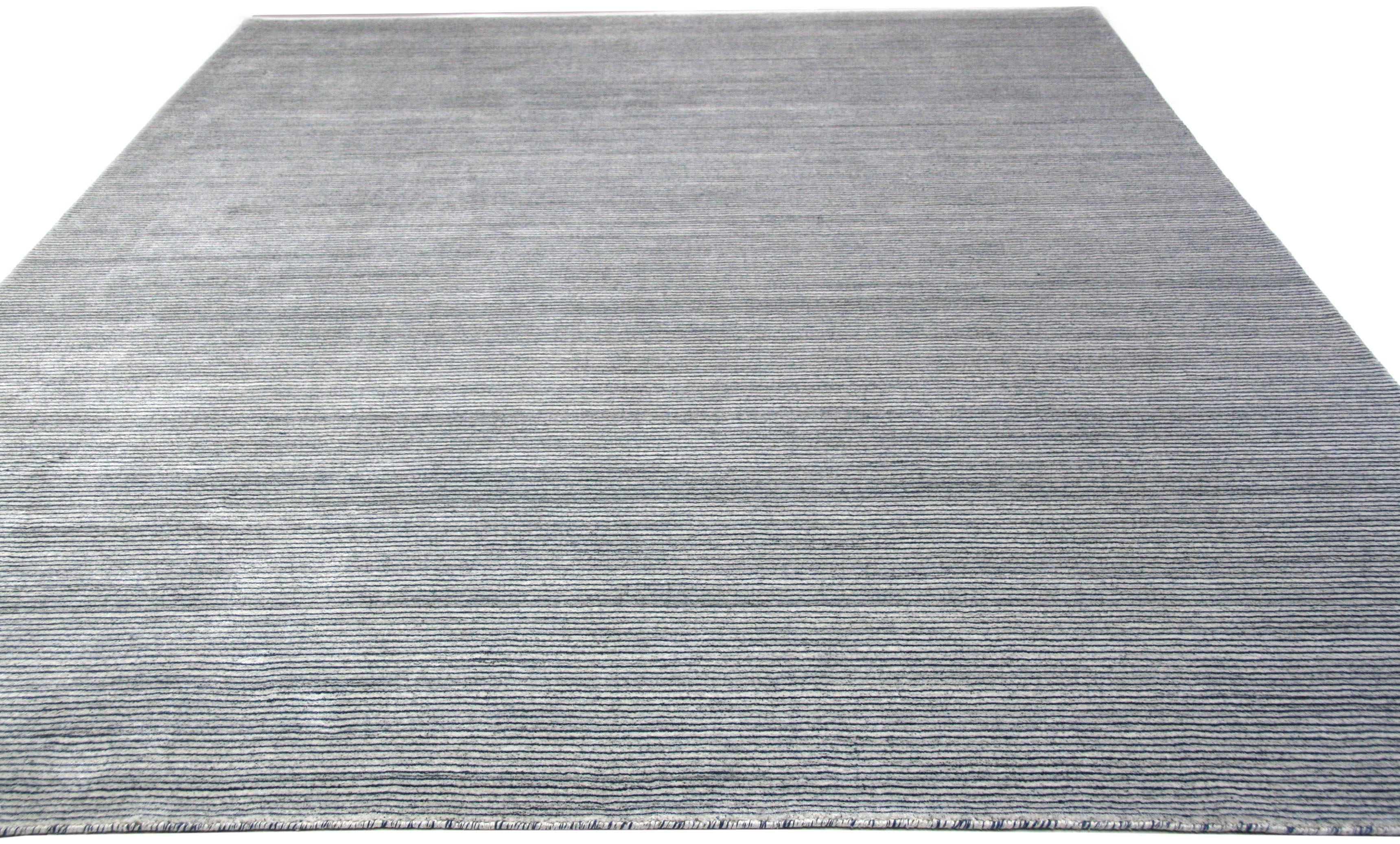 Dark blue alternates with a lightly mottled gray in this bold contemporary area rug. Add subtle pattern to a space or use as a foundation to highlight bold colors or finishes. Wool and vegetal dyes. Hand knotted in India.