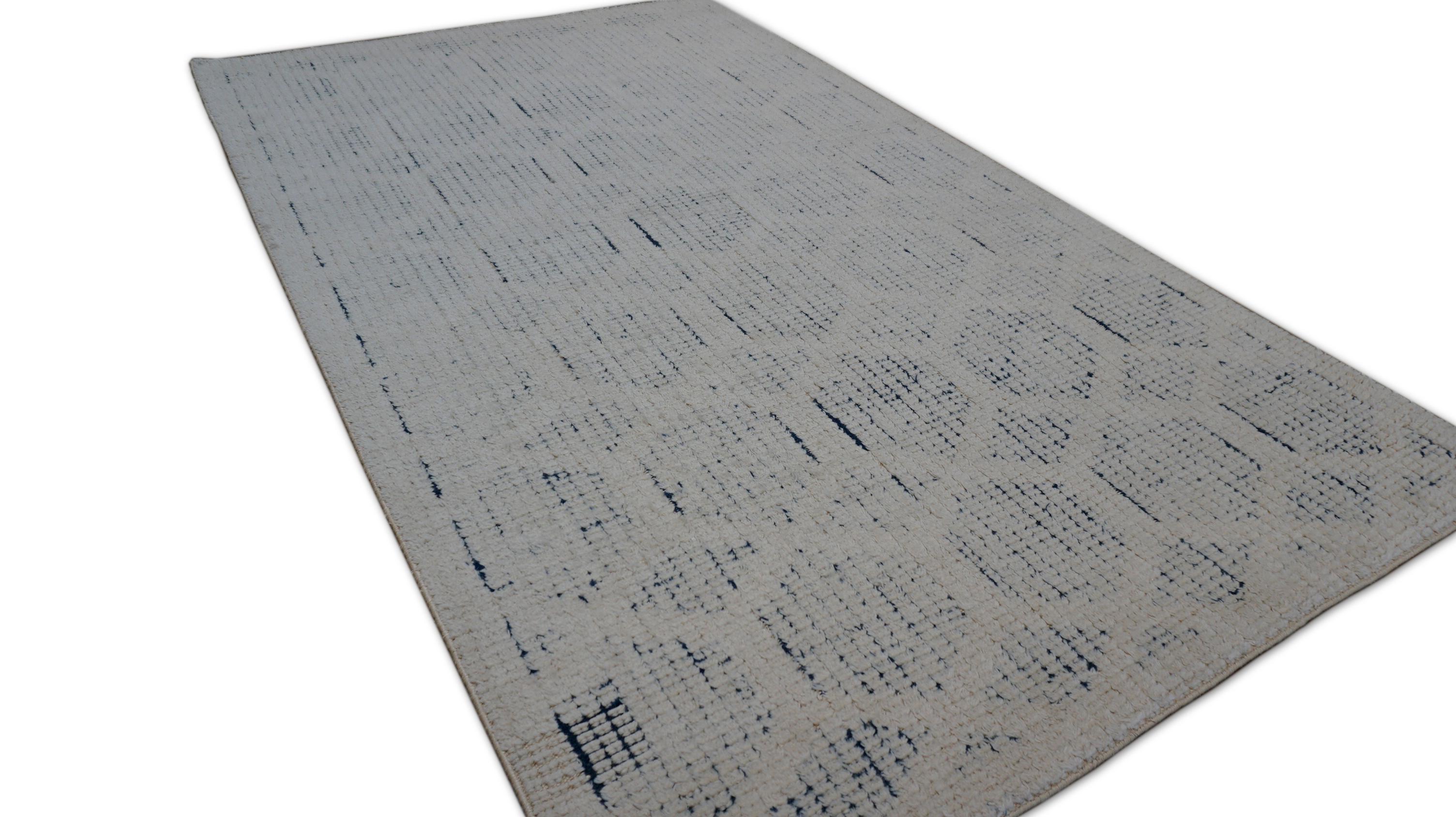 This hand-knotted wool rug features a modern geometric design composed of softly delineated hexagonal shapes arranged in a honeycomb pattern. The subtle tonal contrast between the ivory field and the blue design creates an elegant visual texture,