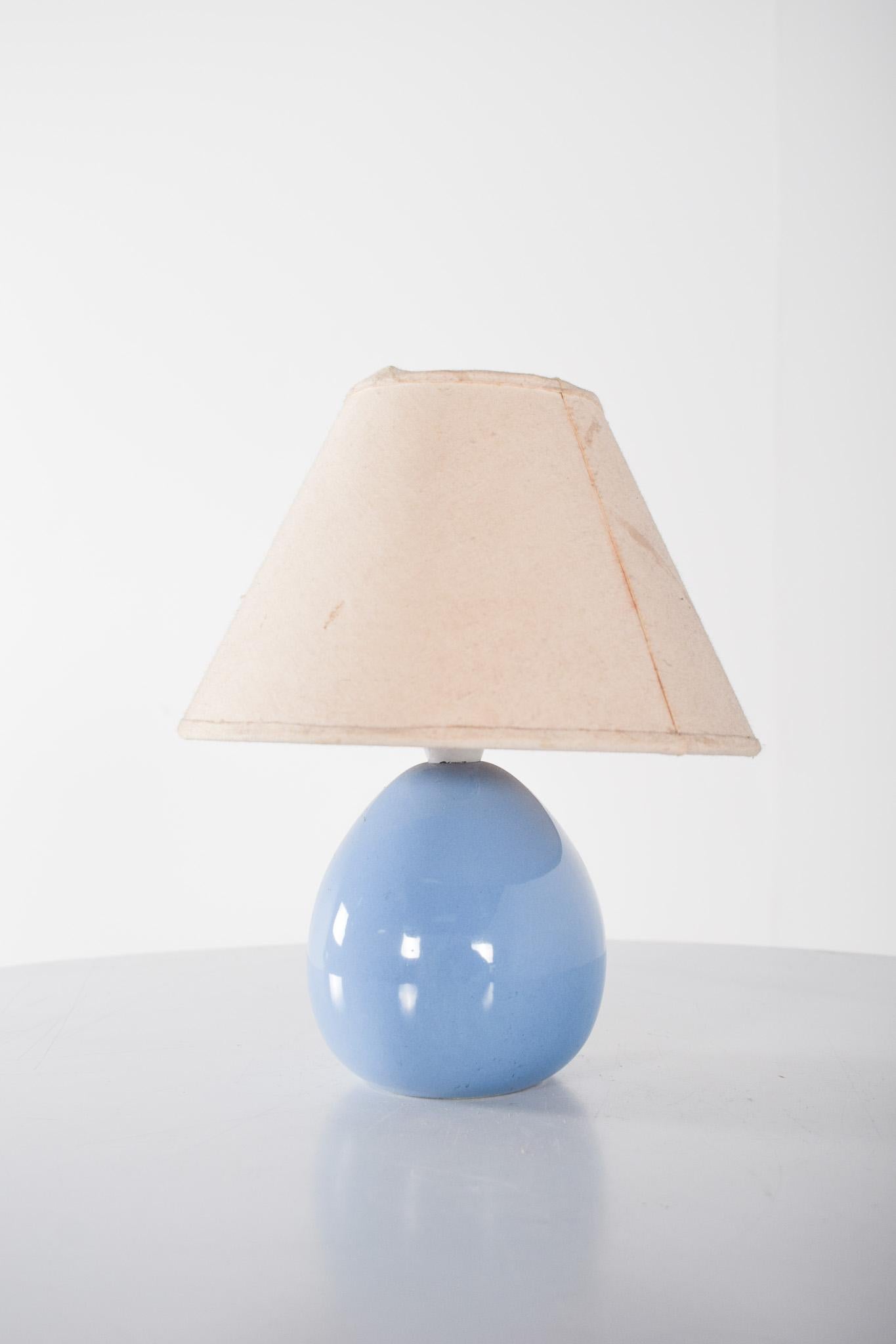 Blue ceramic table lamp. Delicate lamp, ideal for lighting small spaces with a touch of charm. The pear-shaped base is made of glazed ceramic in a bright sky-blue shade, giving it a modern, soft look. The surface discreetly reflects light, making it